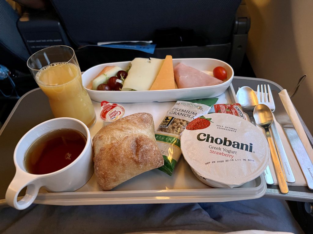 breakfast tray with coffee, juice, bread and cold cuts on a plane