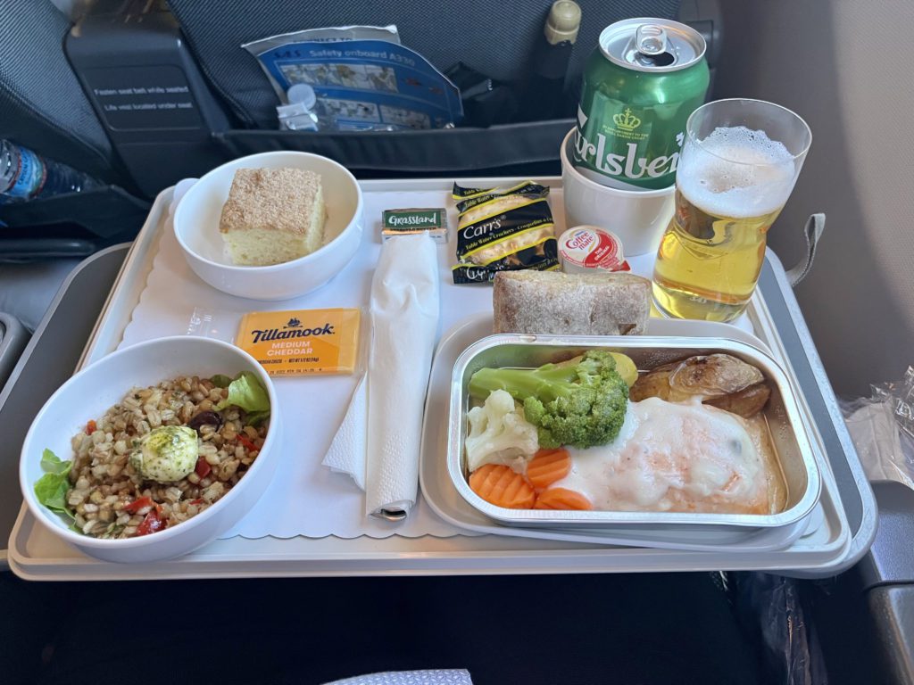 tray on a plane full of food and a glass of beer