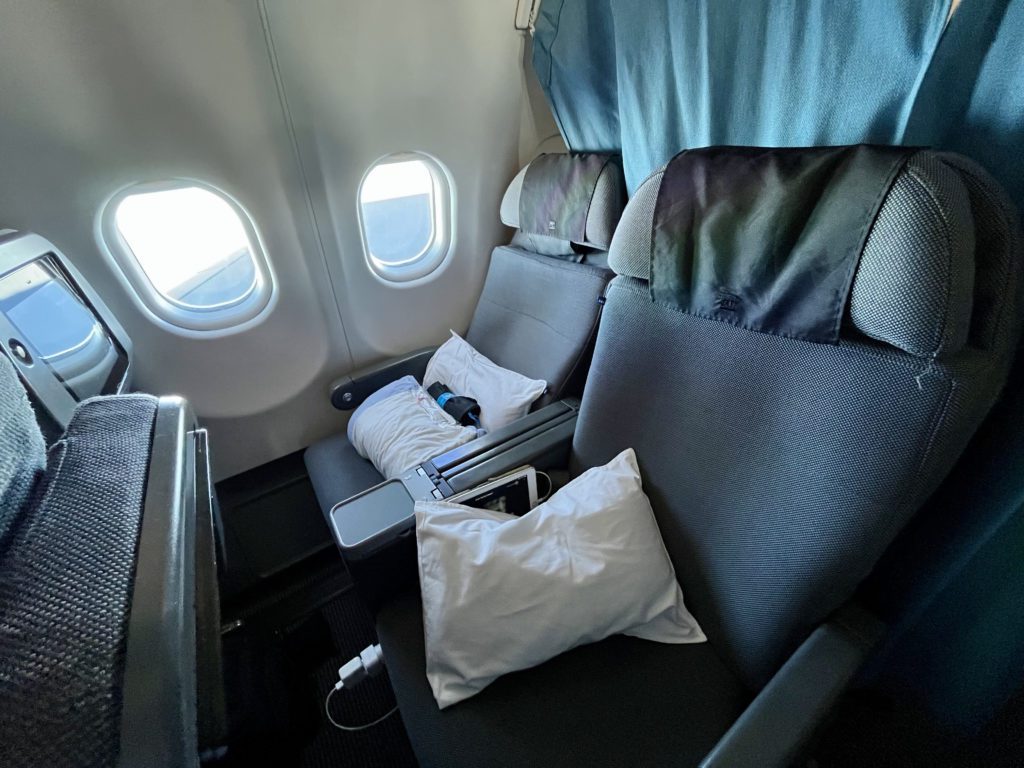an airplane seat reclined with pillows on it