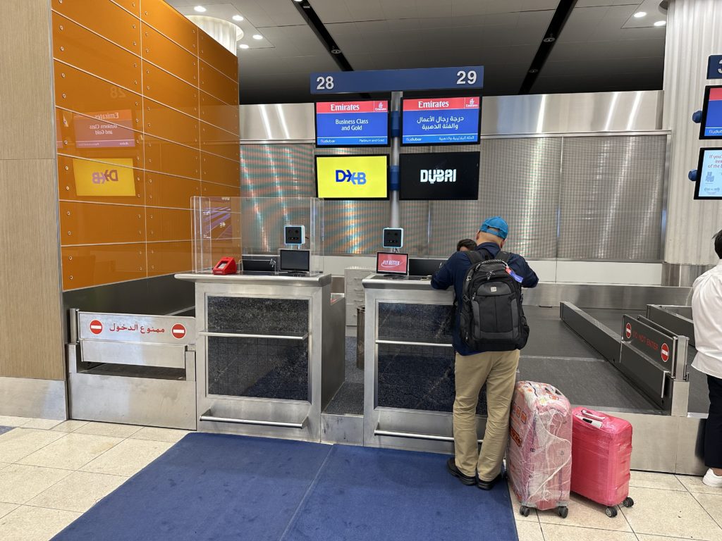 emirates check in counter in Dubai with a man checking two pieces of luggage.
