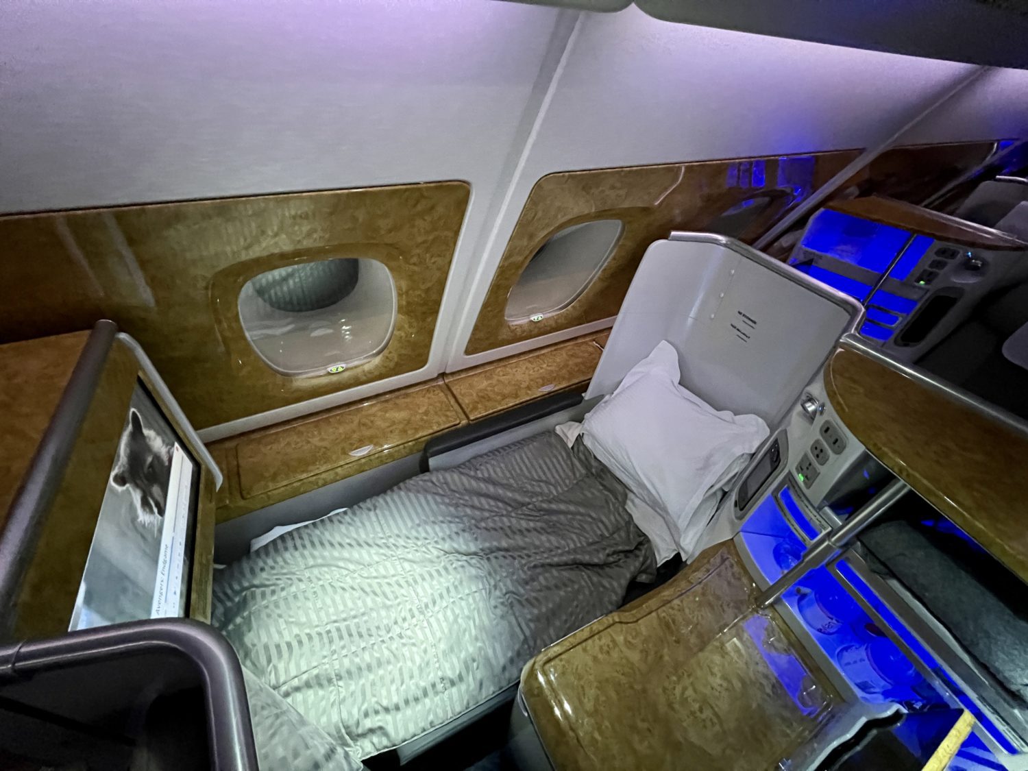 a business class seat reclined into bed mode with a duvet and plush pillow on top