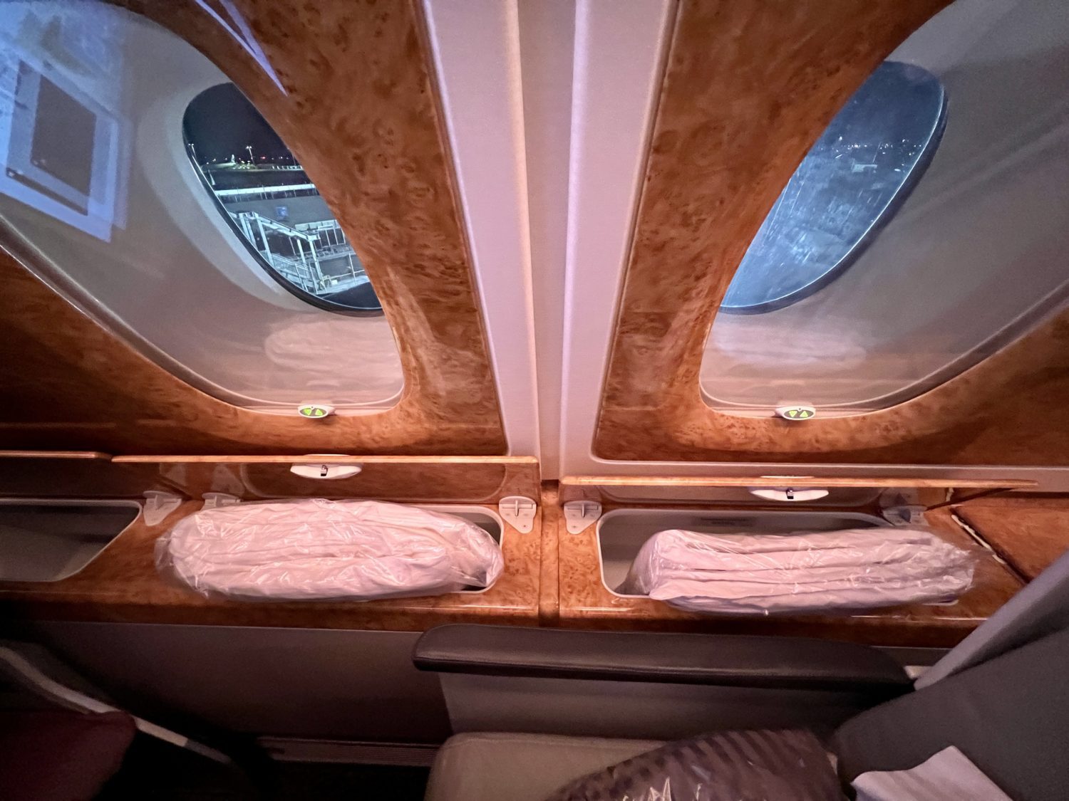a wrapped mattress pad and duvet stuffed inside airplane storage compartments
