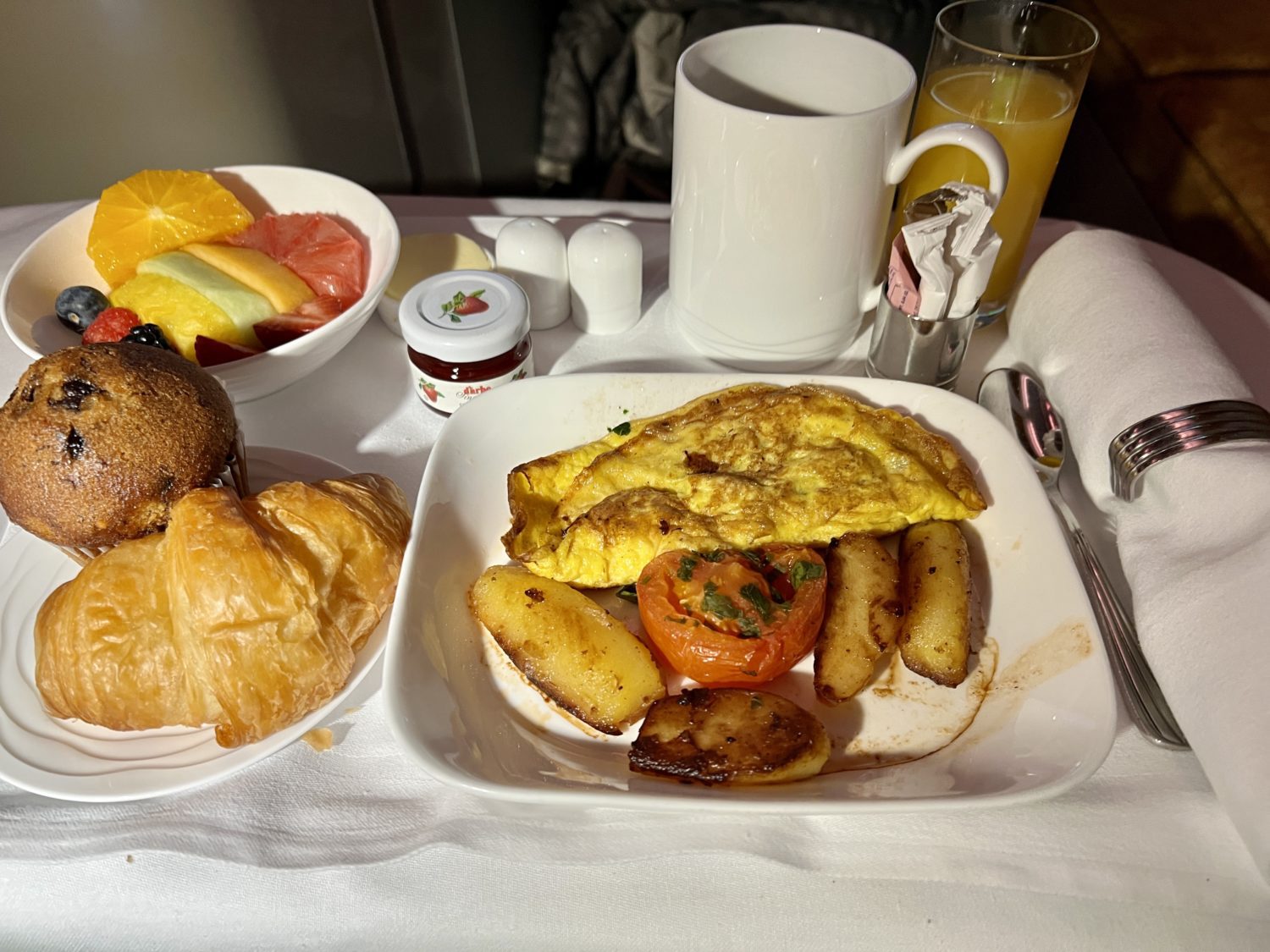 a tray with an omelette and sides, muffin, juice, and fruit