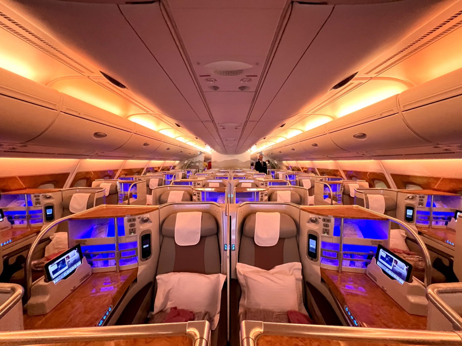 several rows of business class seats inside a dark plane