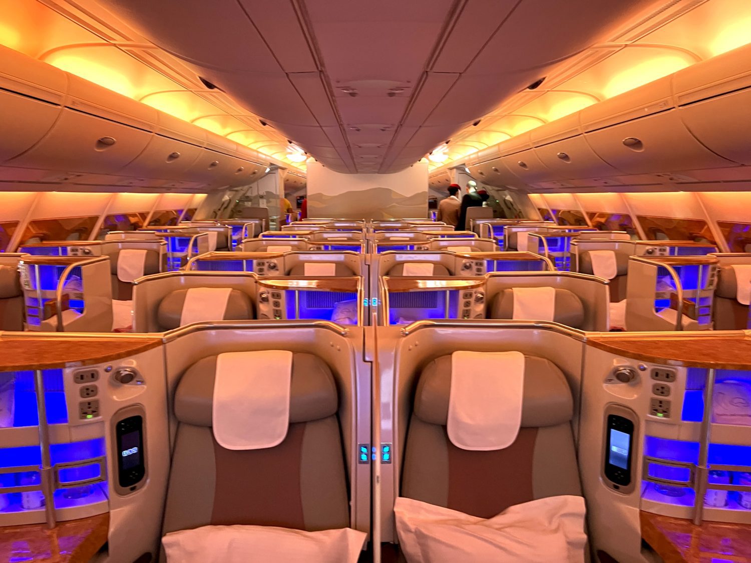 rows of business class seats in the center section of a plane with golden light overhead