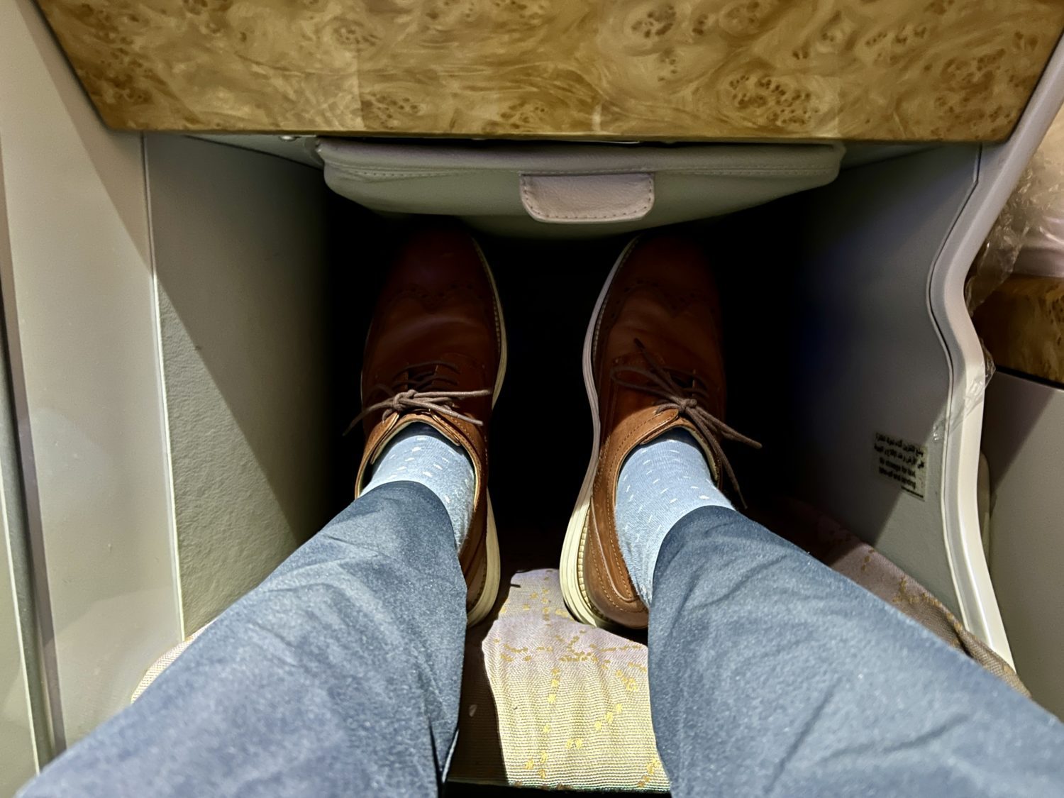 a pair of legs inside of the footwell of a business class seat
