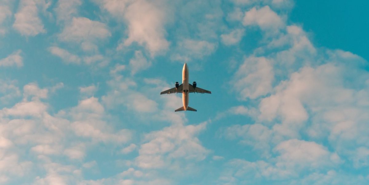 A large jet flying through a cloudy blue sky