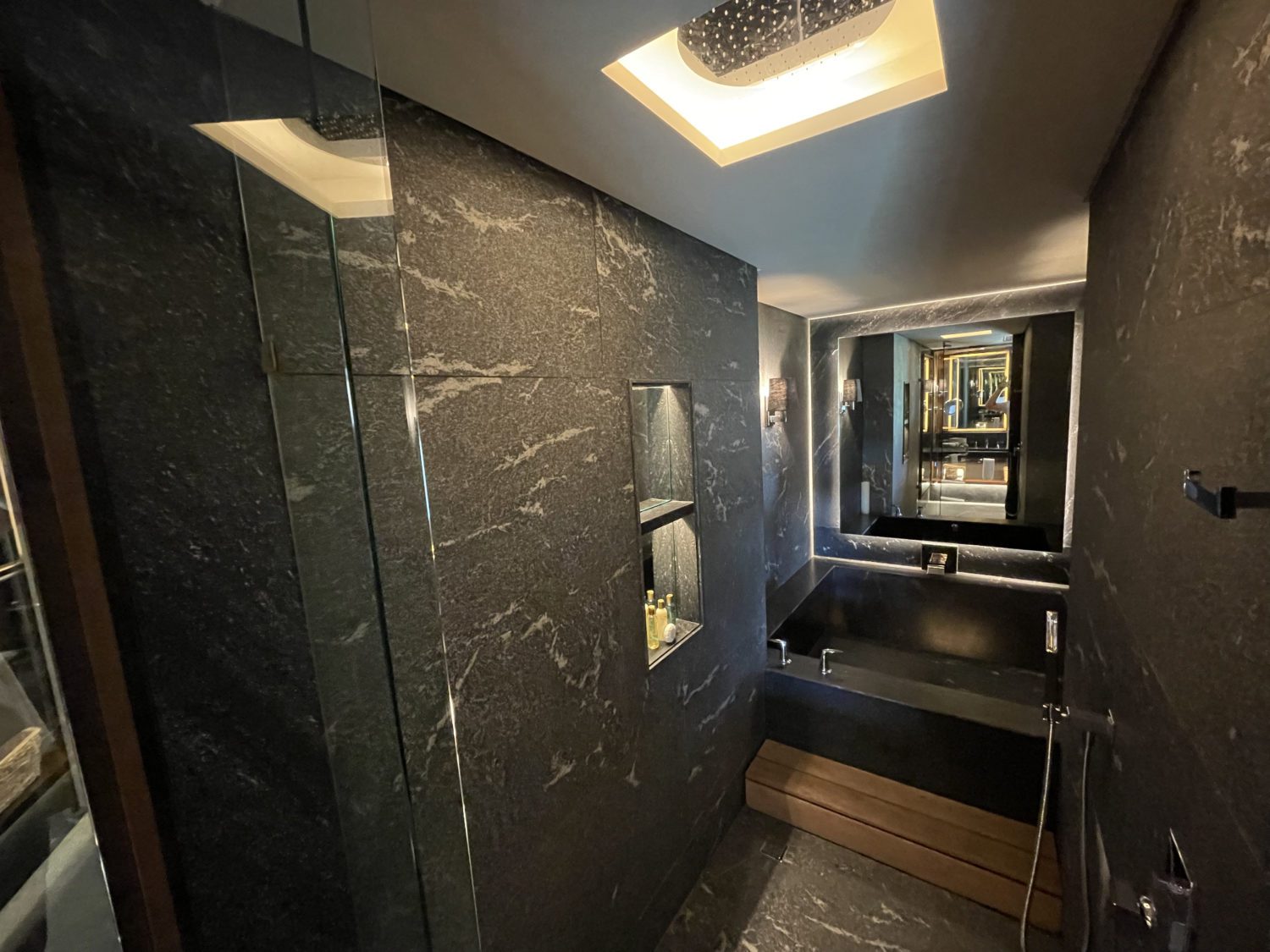 black marble show with a rainfall shower head and a square bathtub. 