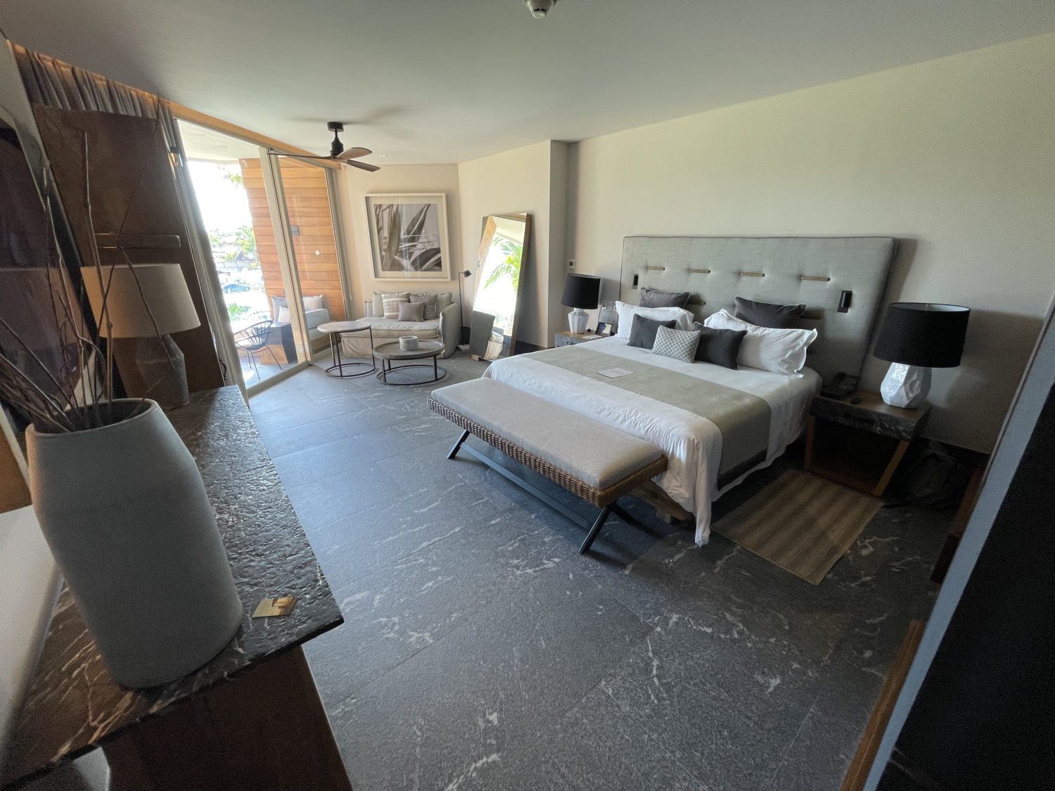 king sized bed in an large hotel room with a sliding glass door leading to a patio