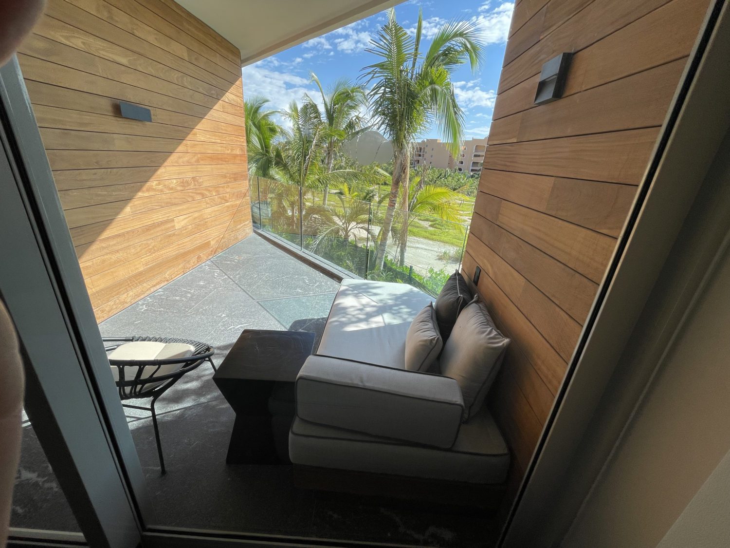 Secrets Moxché Playa del Carmen: An Upscale, All-Inclusive Resort on the Beach 61 small patio off a hotel room with a chaise lounge and small chair facing some palm trees.