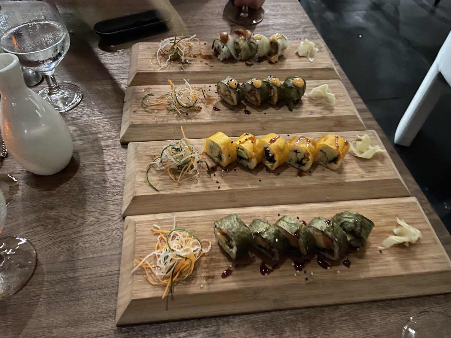 four trays with various sushi rolls
