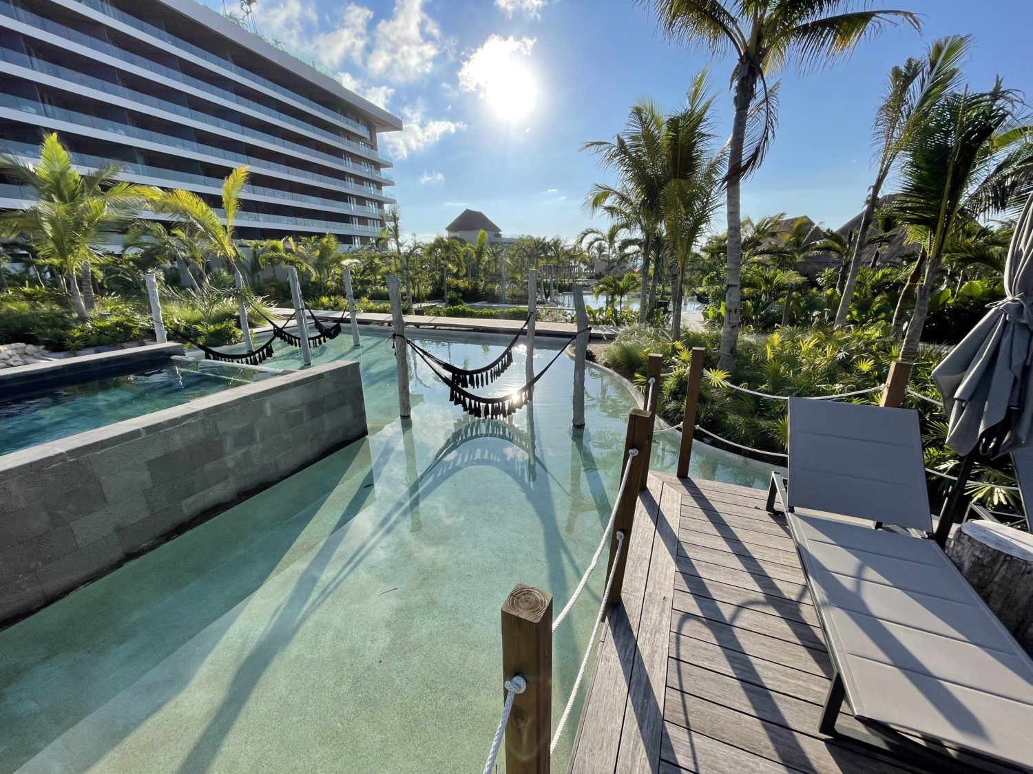 a pool with hammocks and a small deck with beach loungers