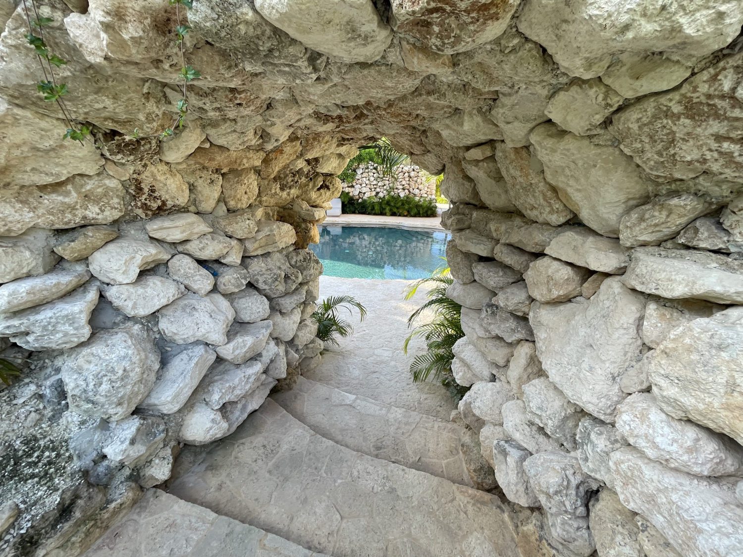 a rocky tunnel leading to a man-made cenote pool 