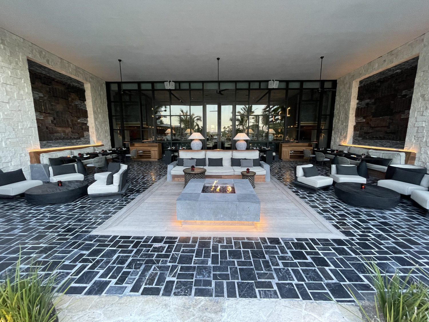 large seating area with stone floors, a stone fire bit and lots of couches 