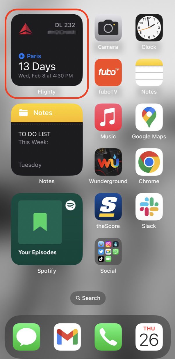 A screenshot of the lock screen showing a flight to Paris in 13 days on Delta in the top left corner of a page full of apps. 