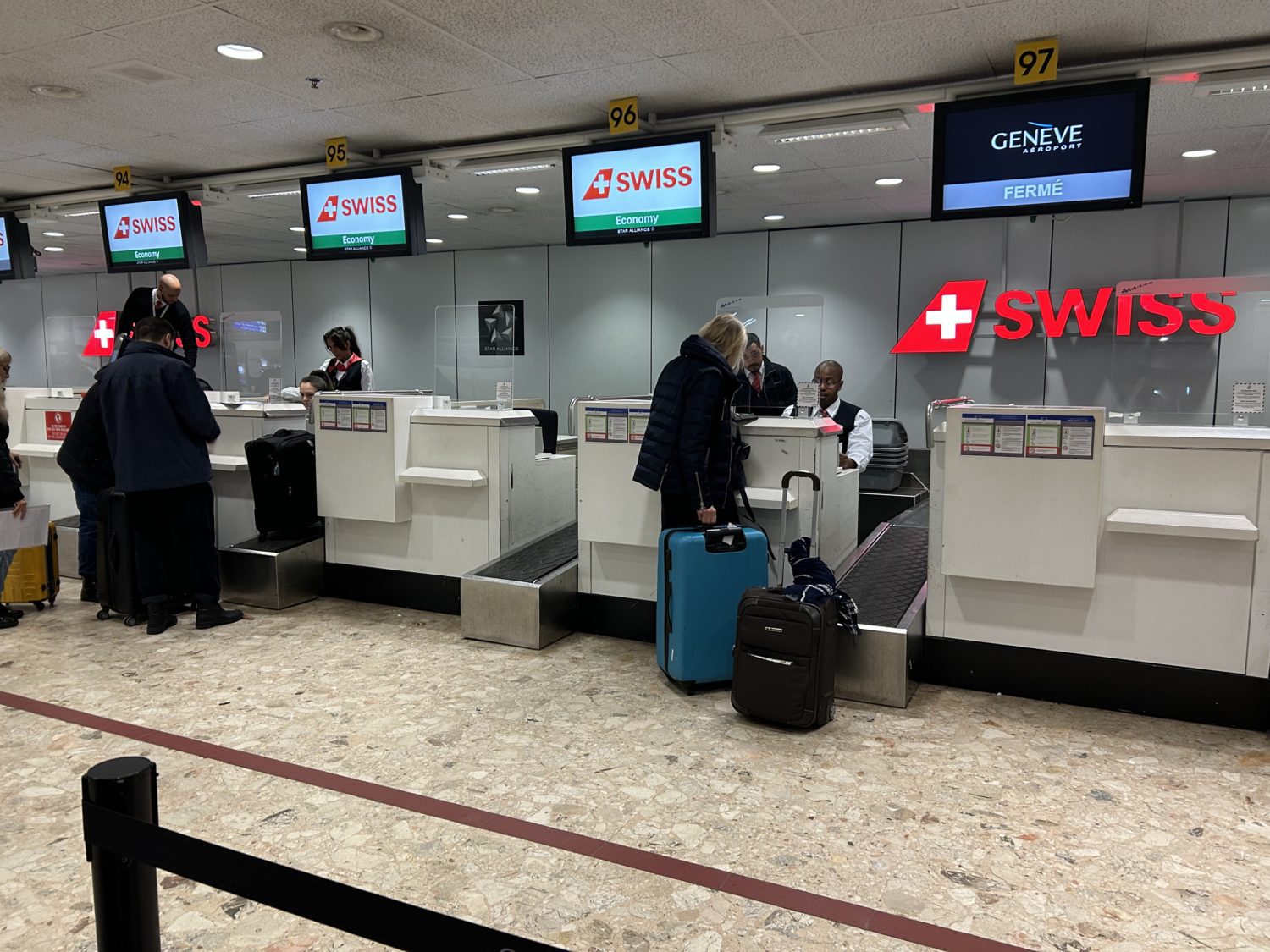 Travelers at the desks at the check-in area for SWISS flights at Geneva airport. 