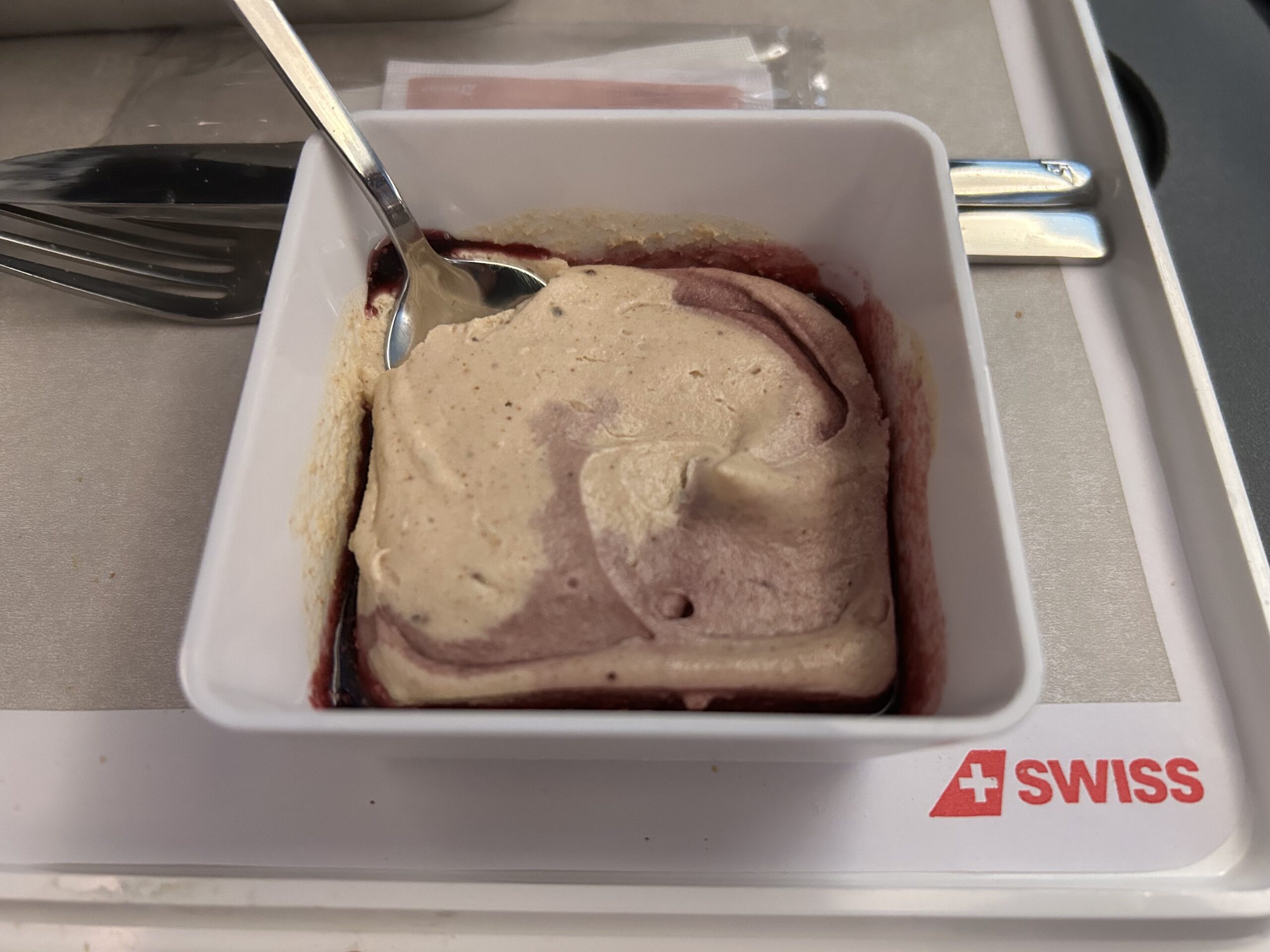 A creamy raspberry dessert with the SWISS Airlines logo on the tray table. 