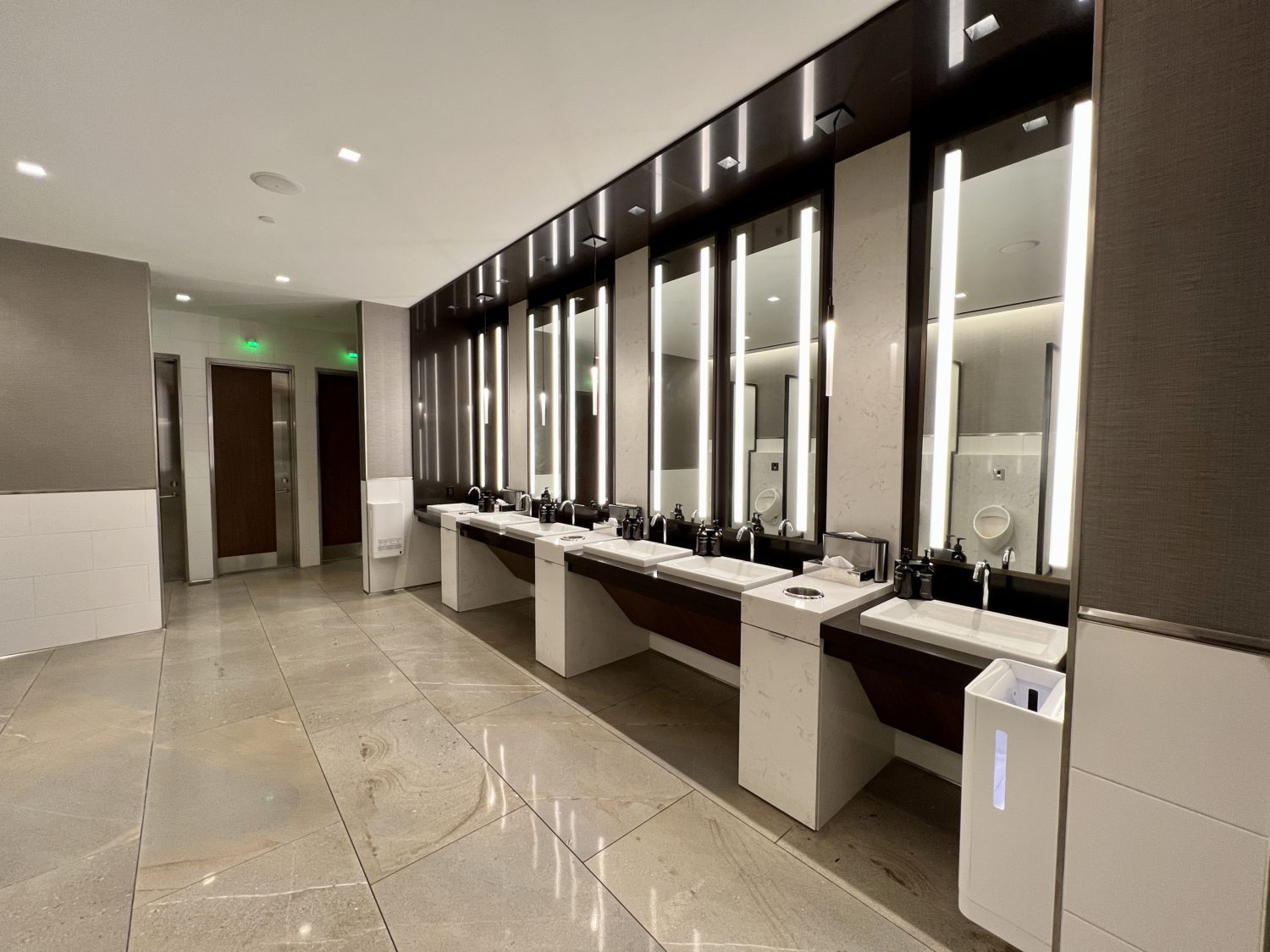 bathroom with several sinks and backlit mirrors