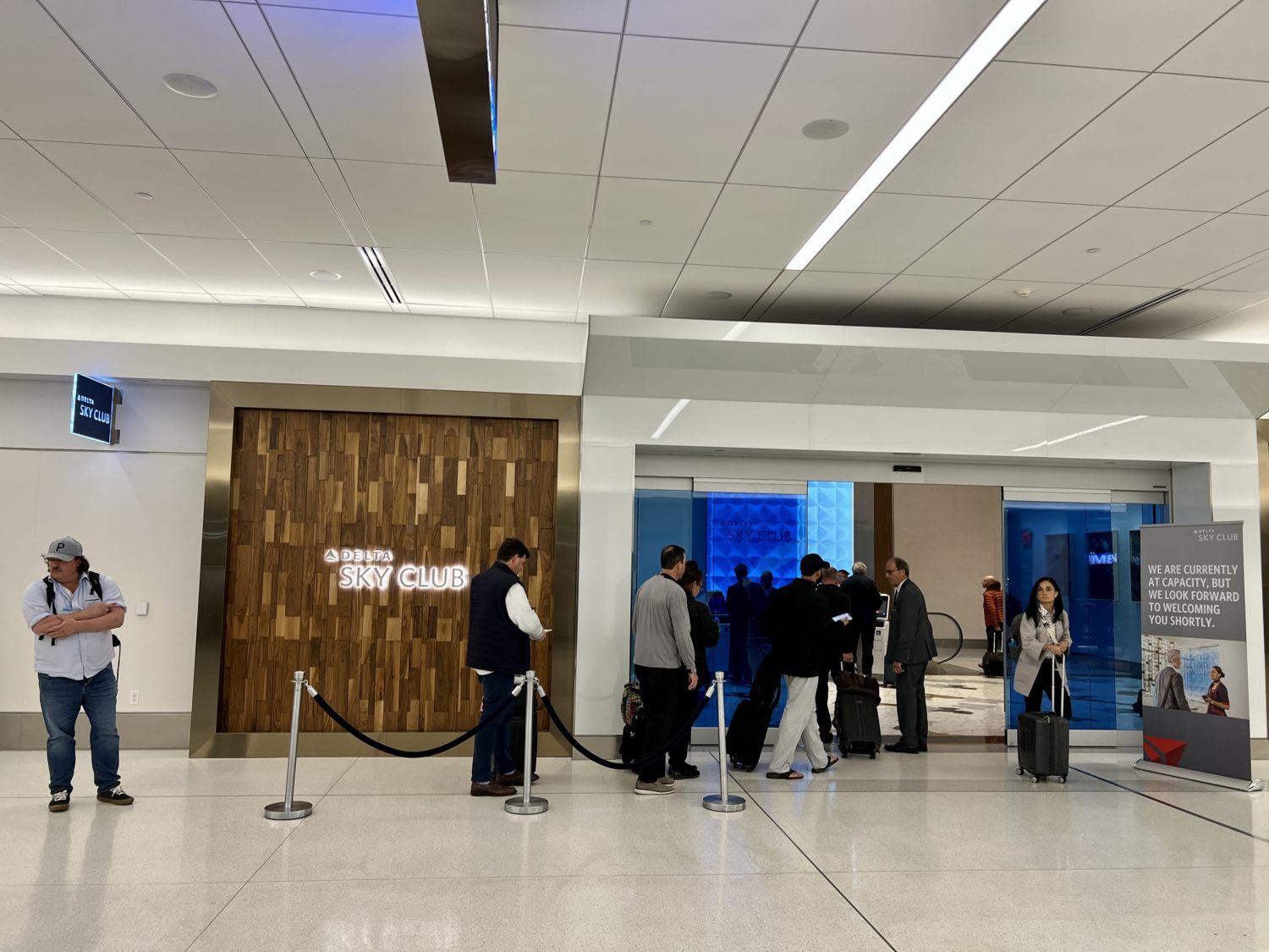 several passengers lined up waiting to enter the delta sky club