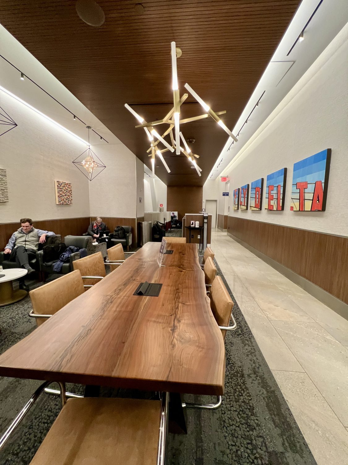 long wooden table with a golden light fixture overhead