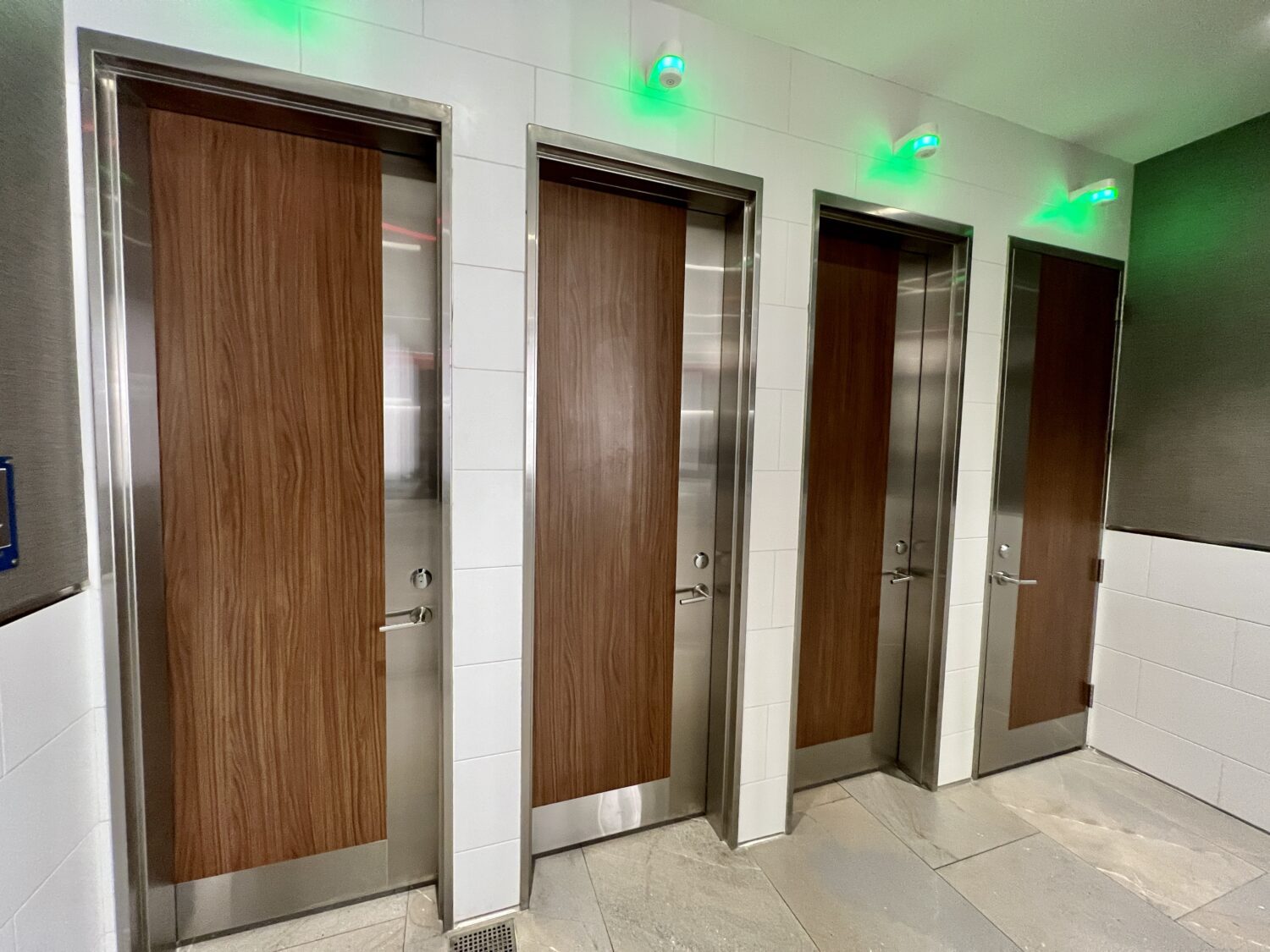 bathroom stalls with green lights overhead