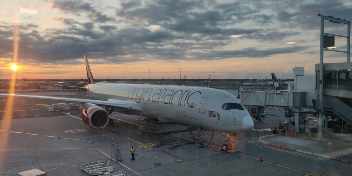 virgin atlantic plane sitting at the gate with the sun setting