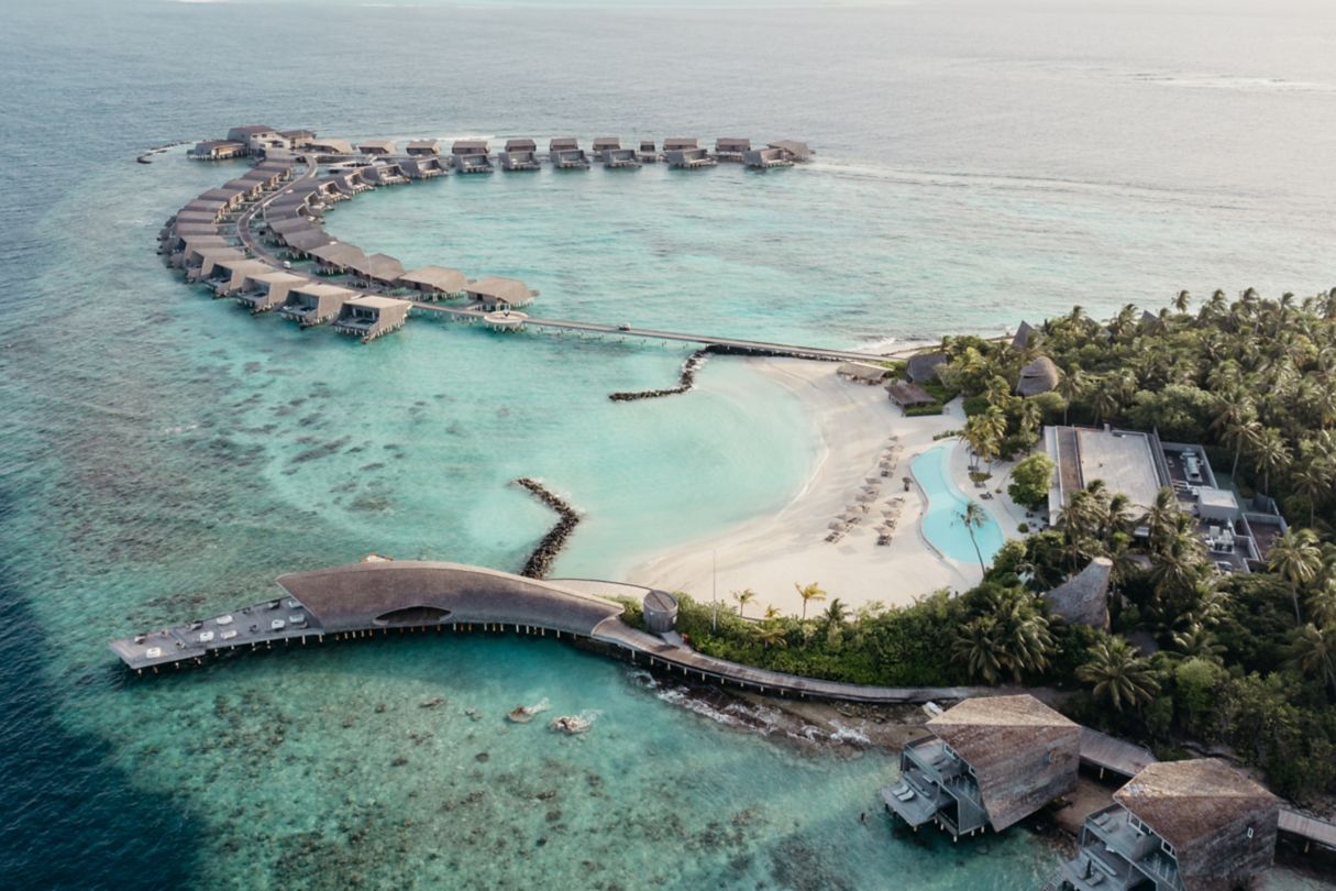 a resort with overwater villas and a sandy beach with a pool 
