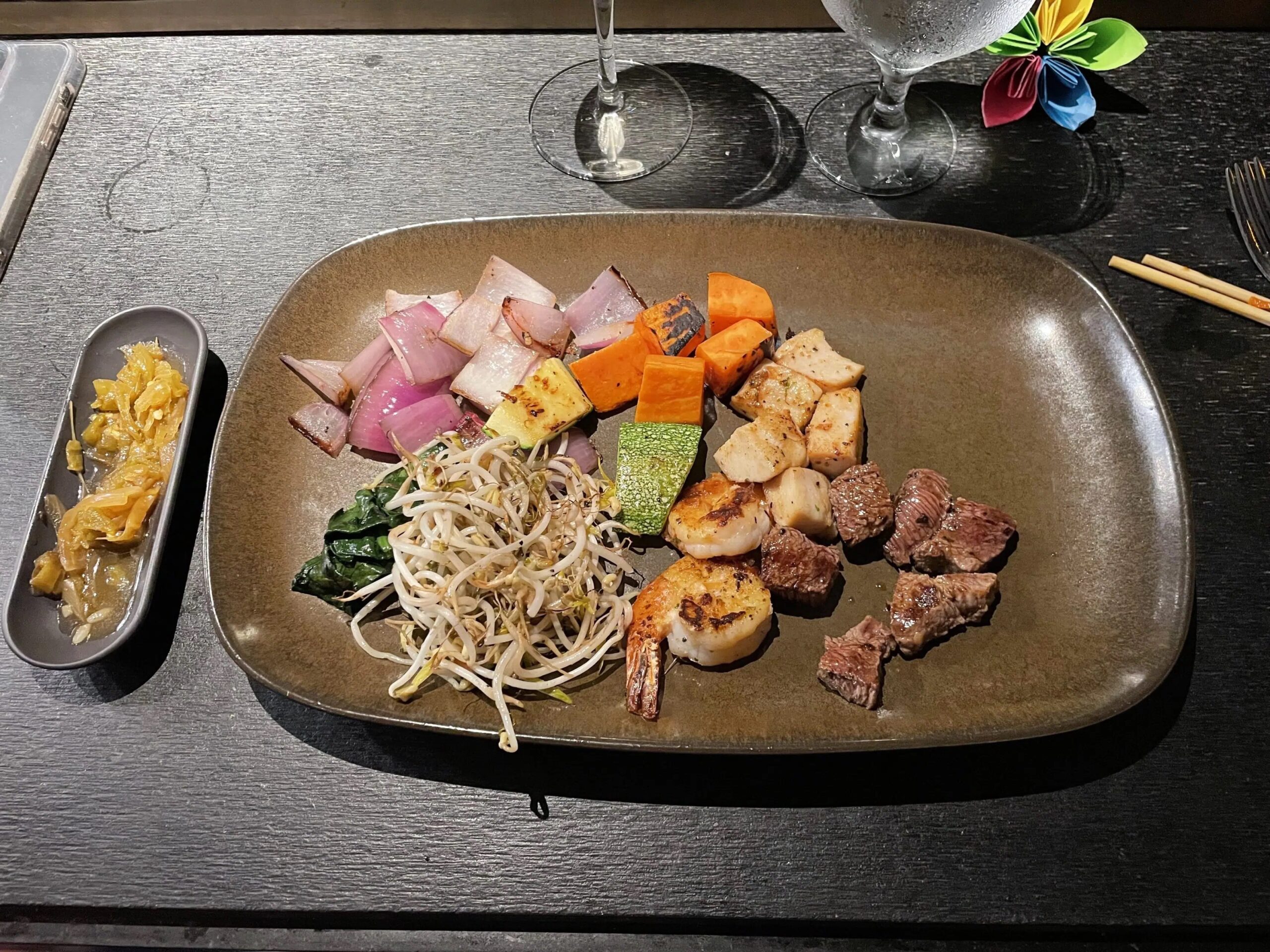 A plate with teppanyaki noodles, shrimp, steak, oniones, carrots, and zucchini. 
