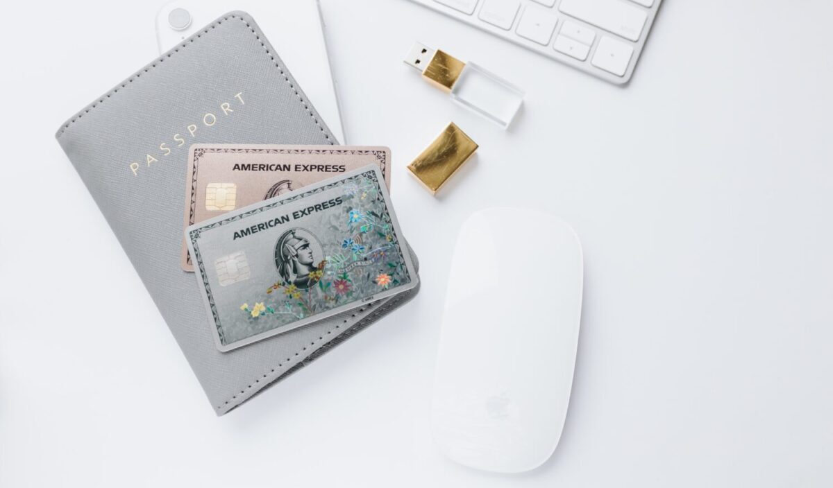 American Express Gold and Platinum Cards on a passport wallet by a computer keyboard and mouse.