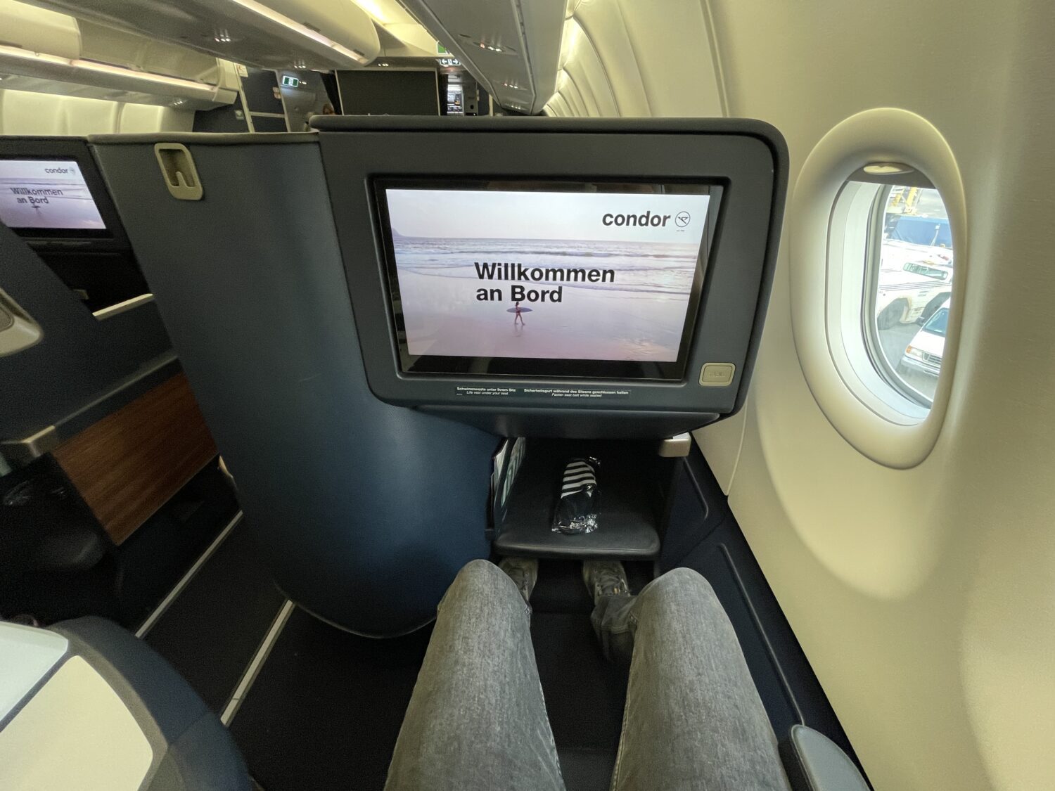 a tv screen and legs in an airplane seat