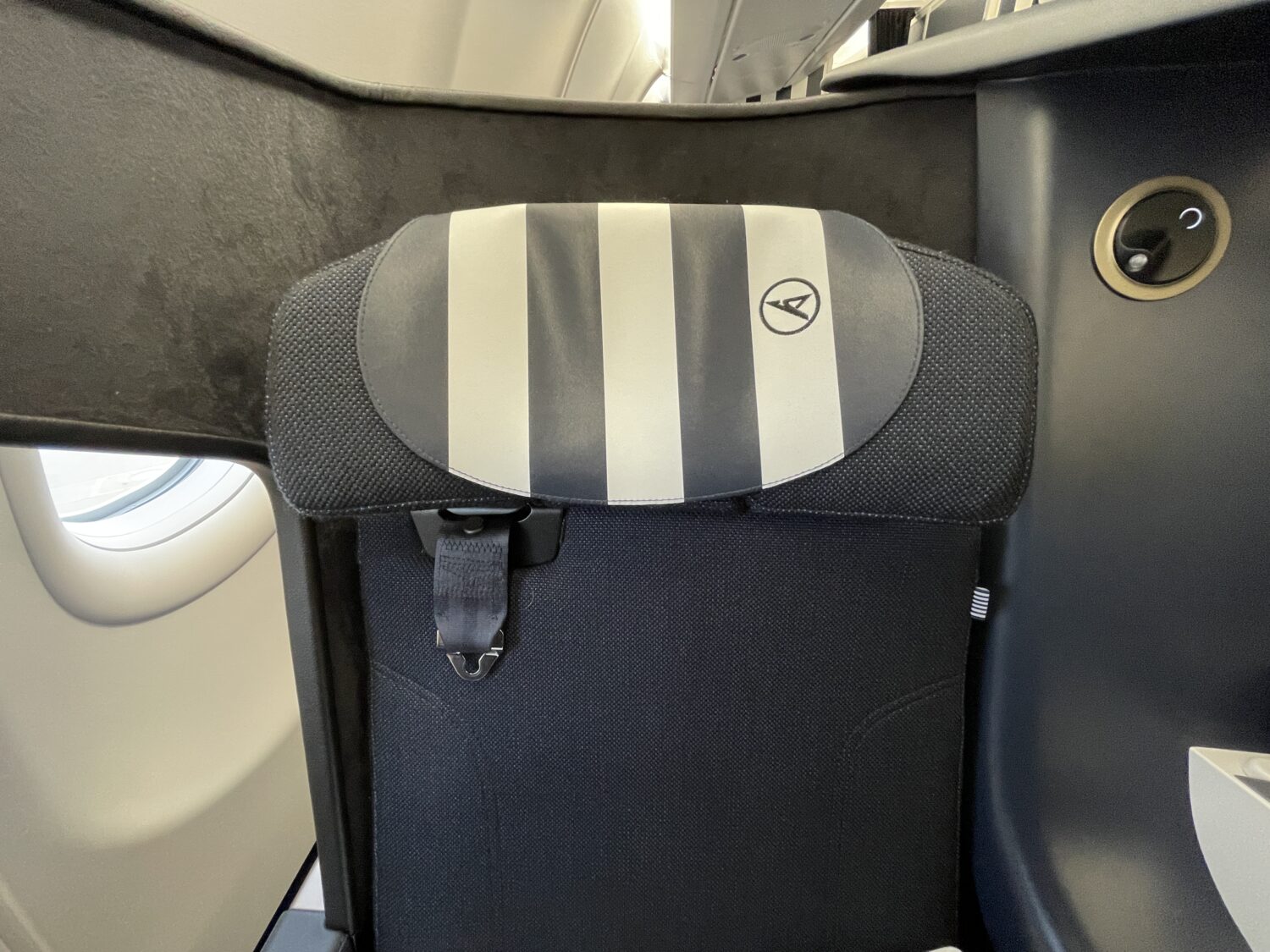 blue and white striped headrest on an airplane seat and a reading lamp