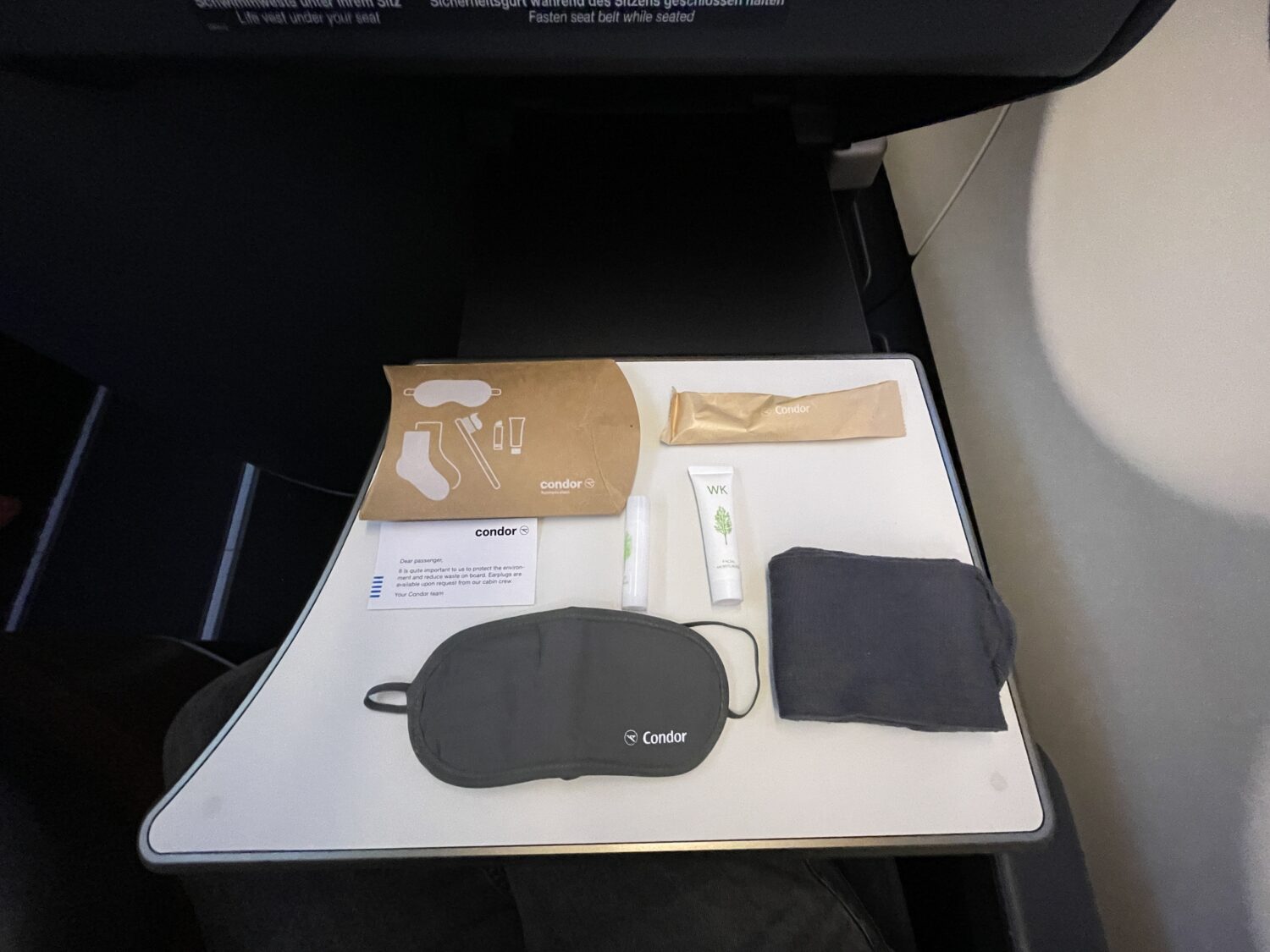 cardboard box, eye mask, socks, toothpaste and a toothbrush in packaging on a tray table