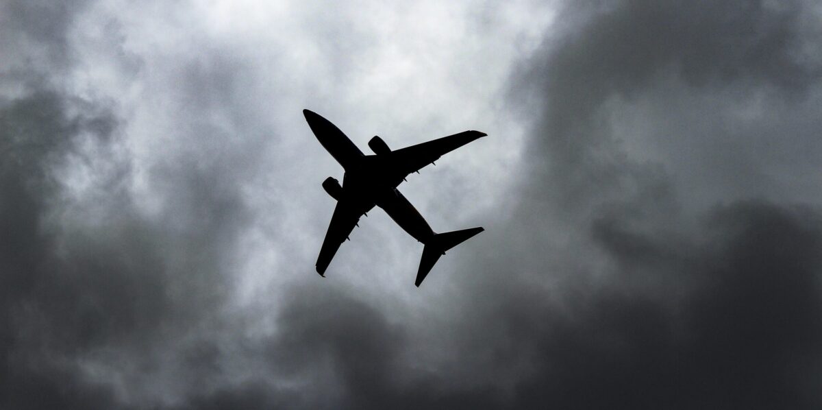 plane from below flying through dark clouds