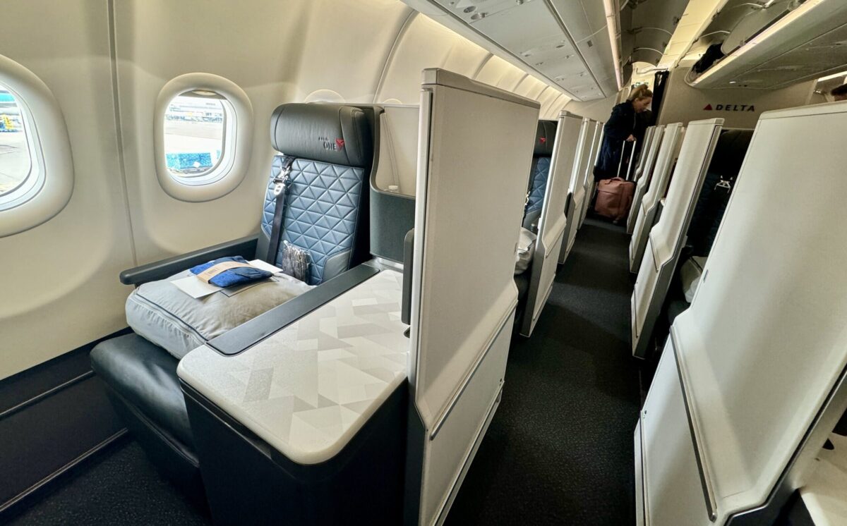 The Best & Worst Planes for Delta One Business Class 15 several rows of business class suites with a passenger and her luggage in the background