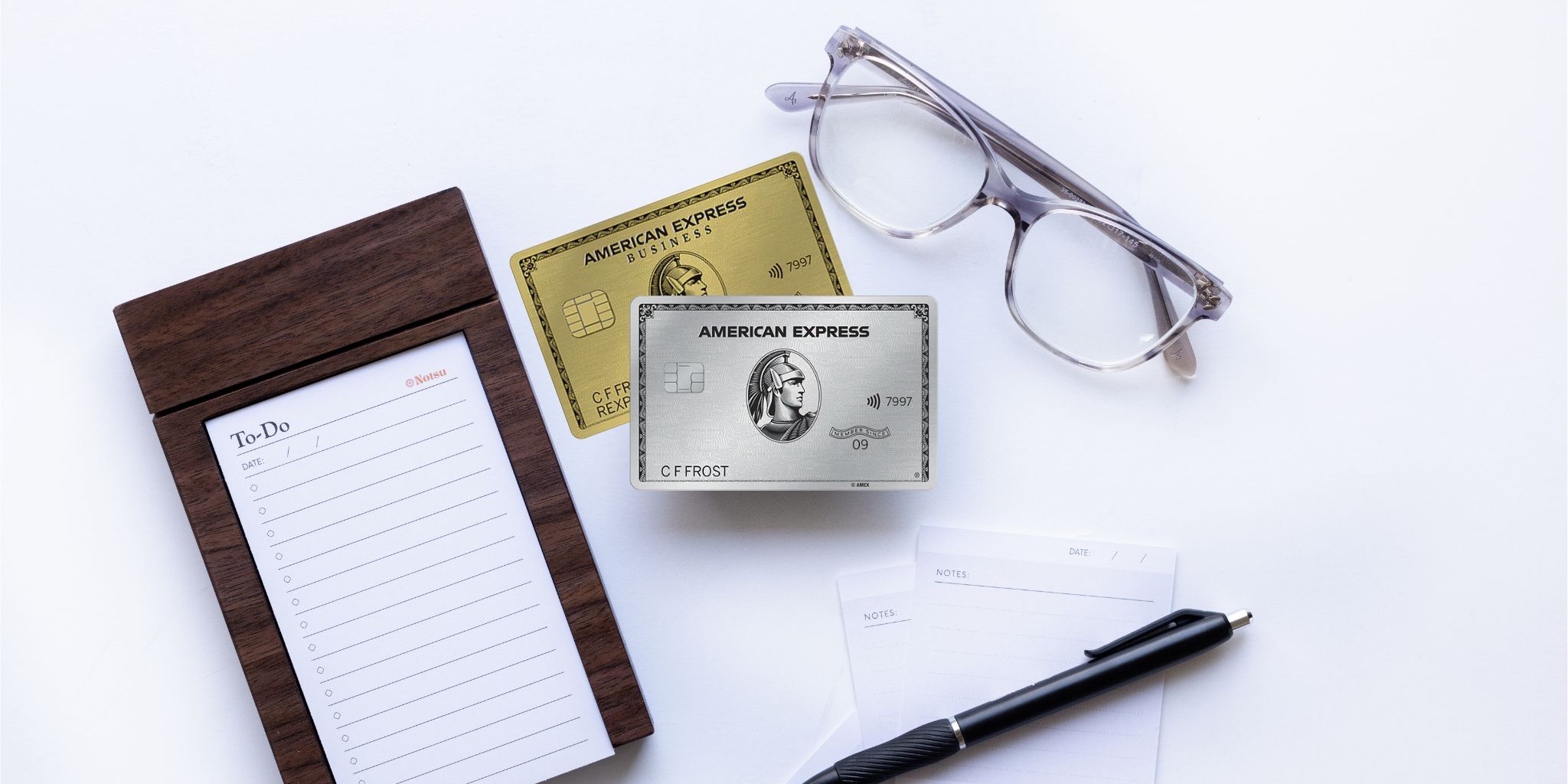 American Express Platinum and Business Gold credit cards with notepad, glasses, and pen
