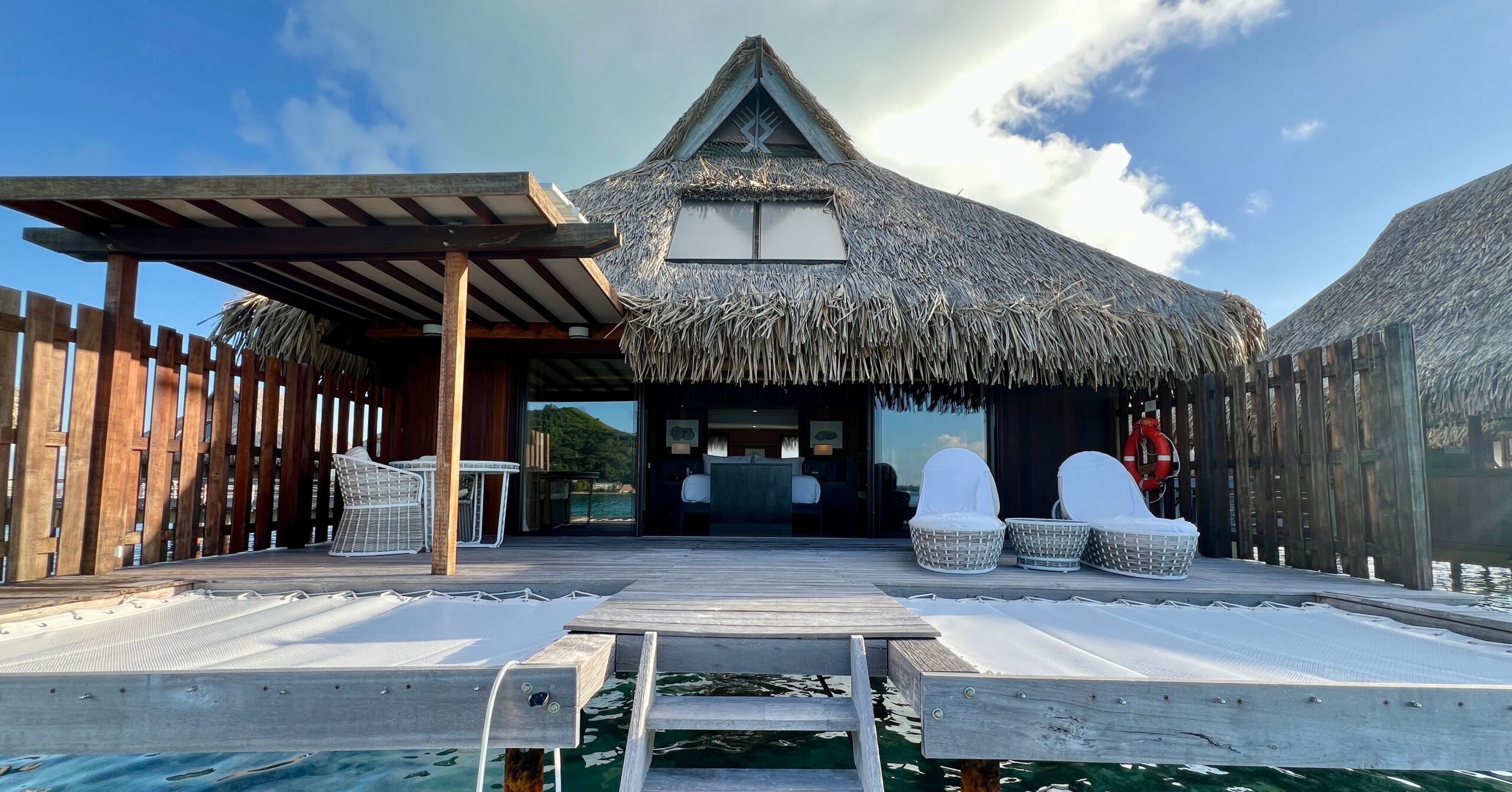 overwater villa with thatched straw roof and chairs on deck