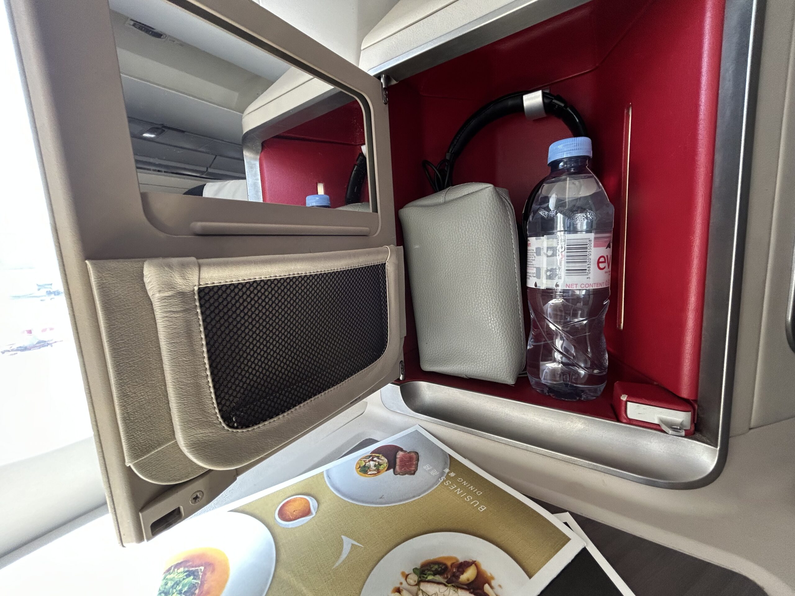 water bottle, amenity kit, and a pair of headphones in a cubby