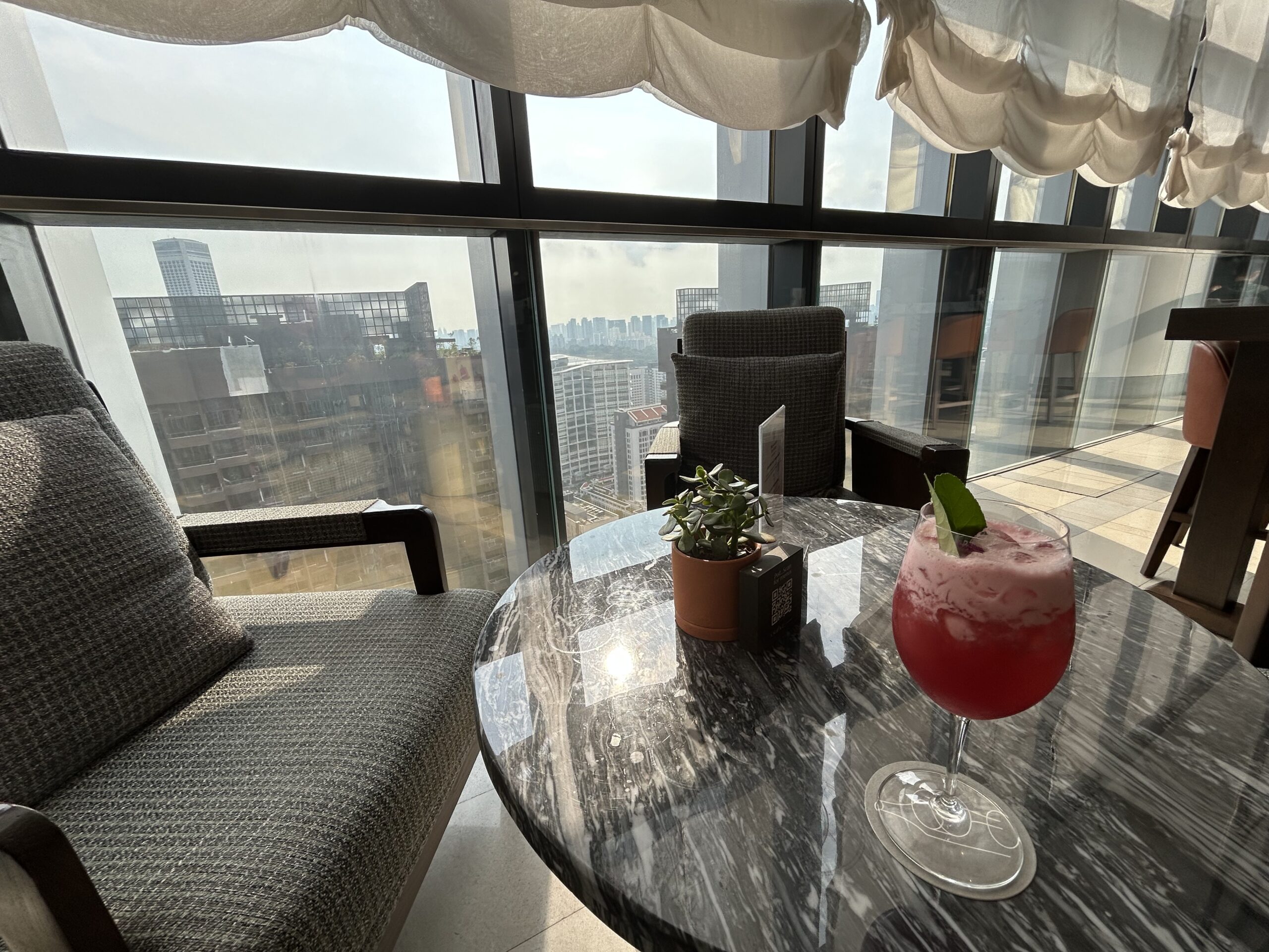 a pink cocktail sitting on a table at a hotel bar