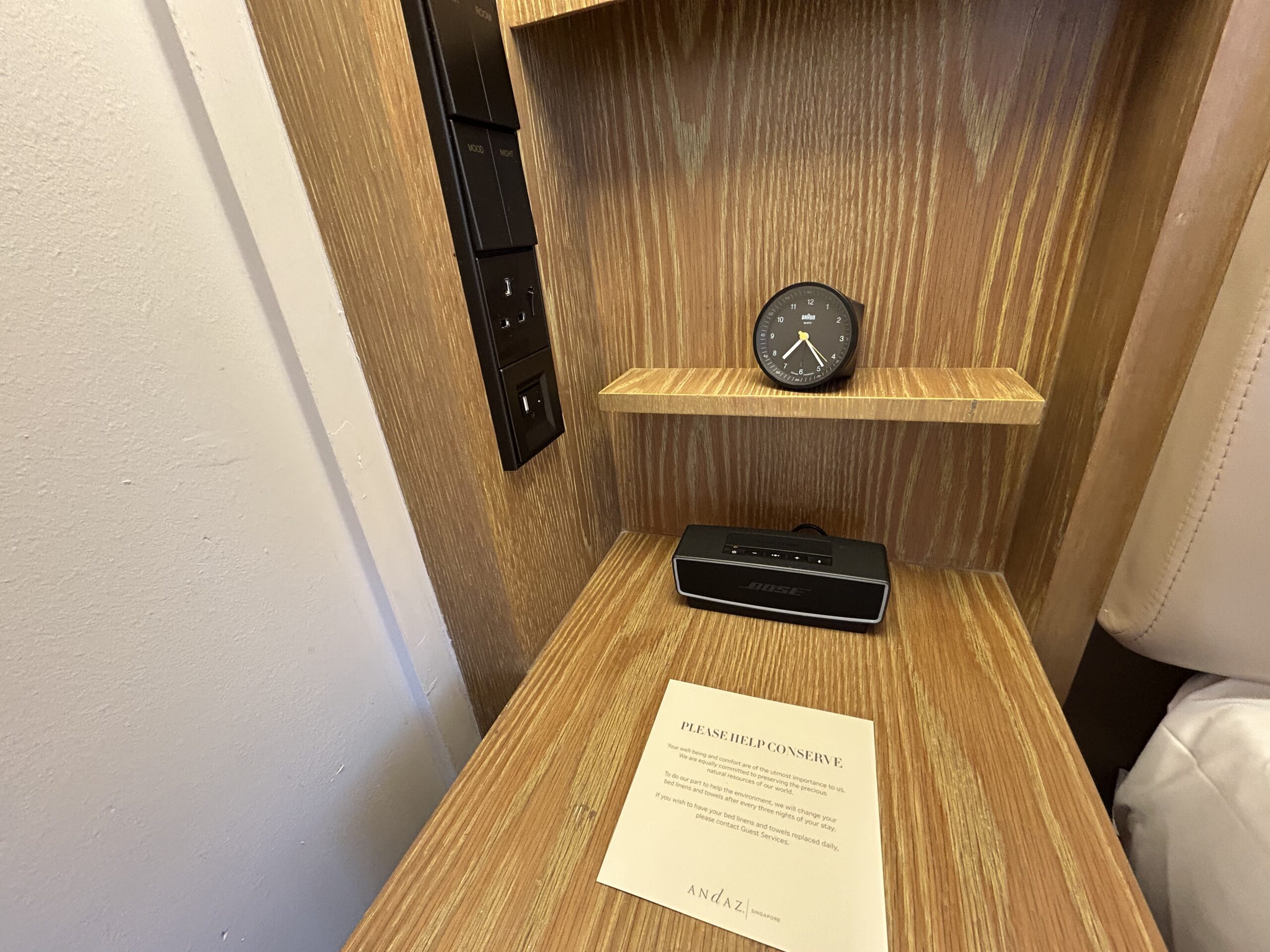 an alarm clock and a portable speaker on a bedside table. 