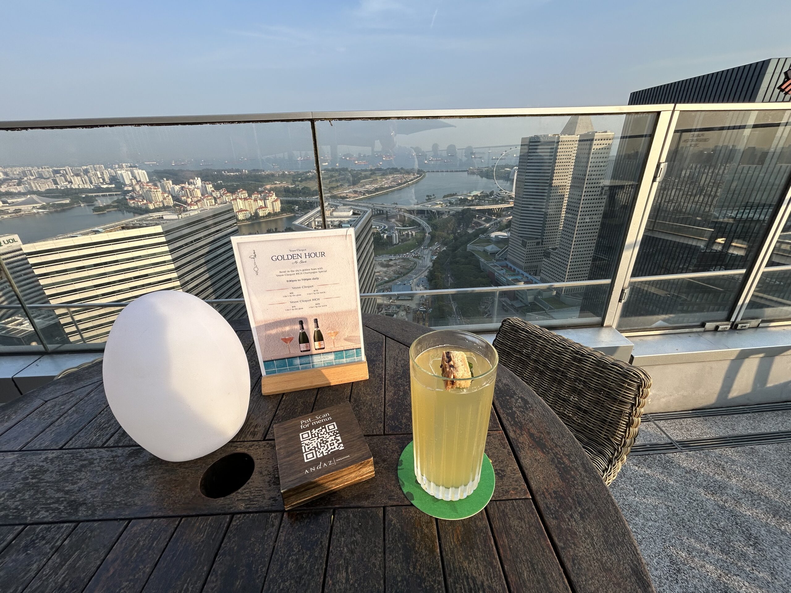 a yellow cocktail on the rooftop terrace overlooking singapore