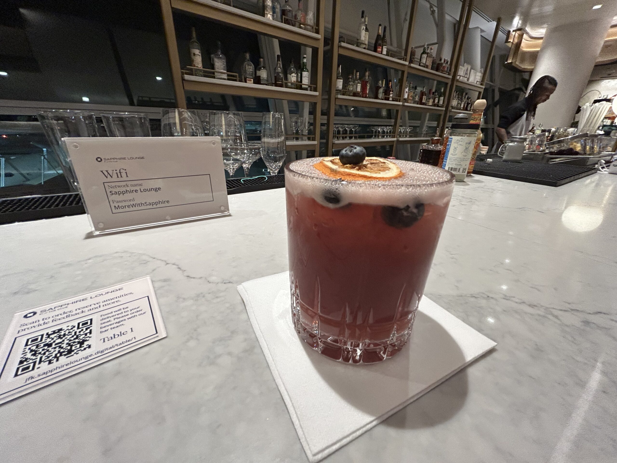 A pink cocktail with blueberries and orange slices