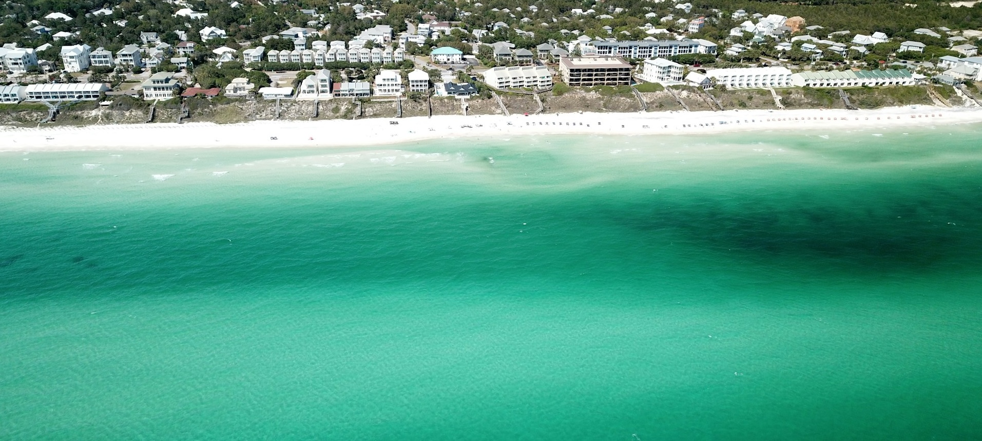 a beach with buildings and blue water