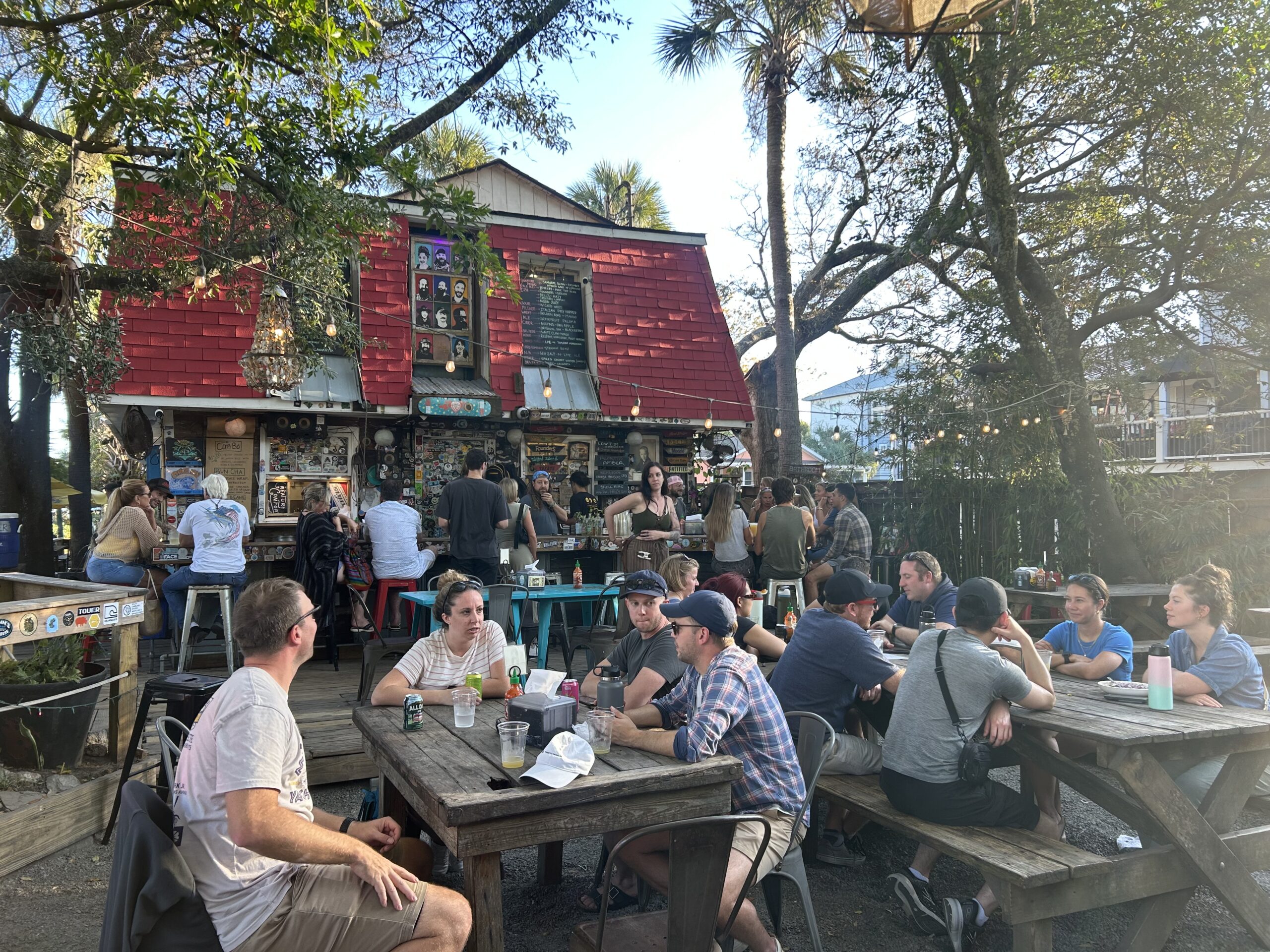 an outdoor restaurant patio with picnic tables and trees for shade