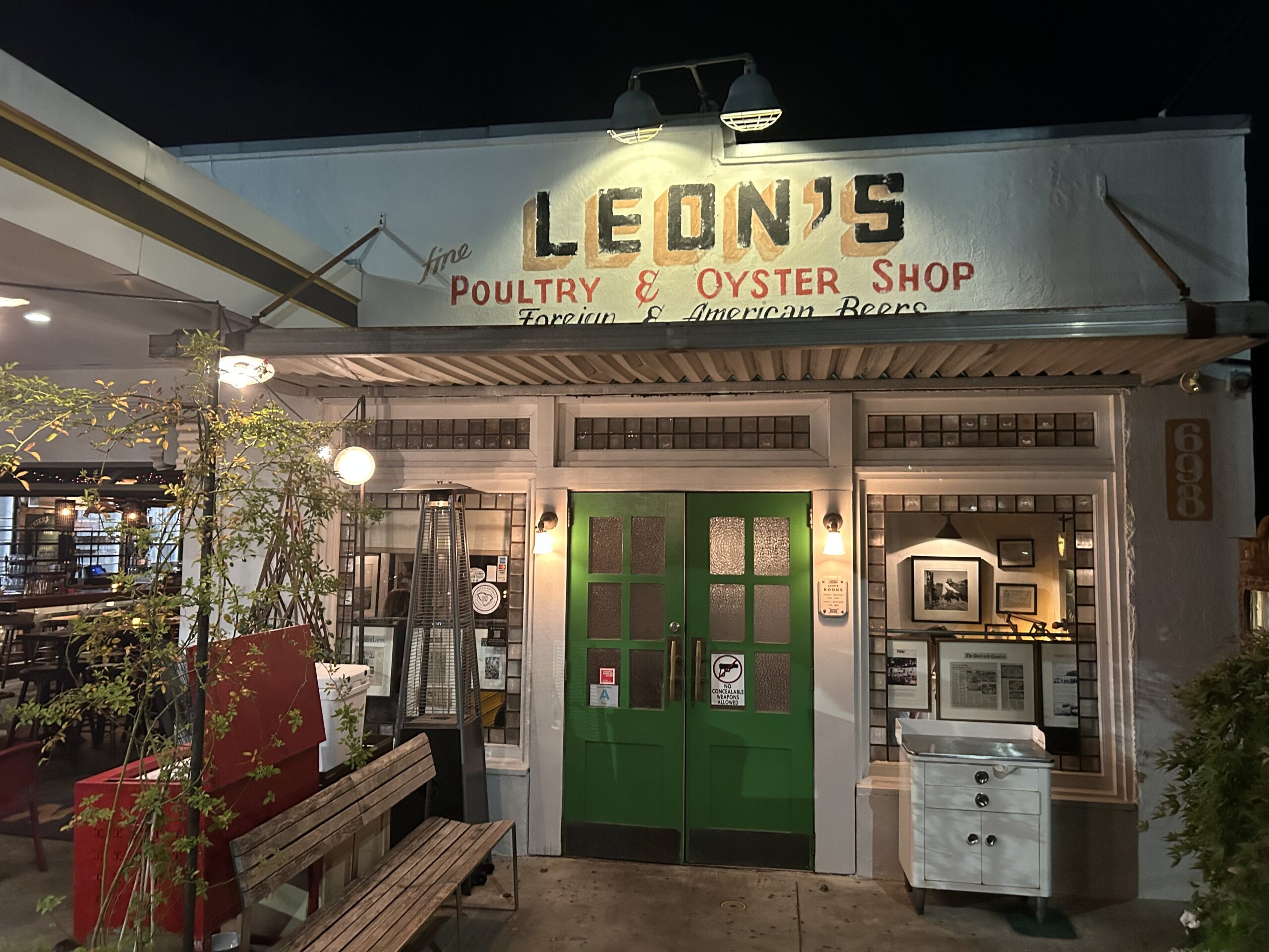 Leon's Poultry and Oyster Shop sign illuminated by an overhead light above the restaurant on a warm night in Charleston. 