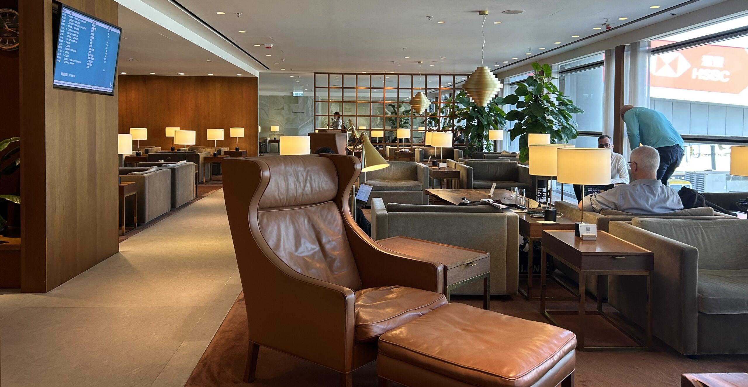 The Pier first class lounge with lounge seating, lamps, and a video board.