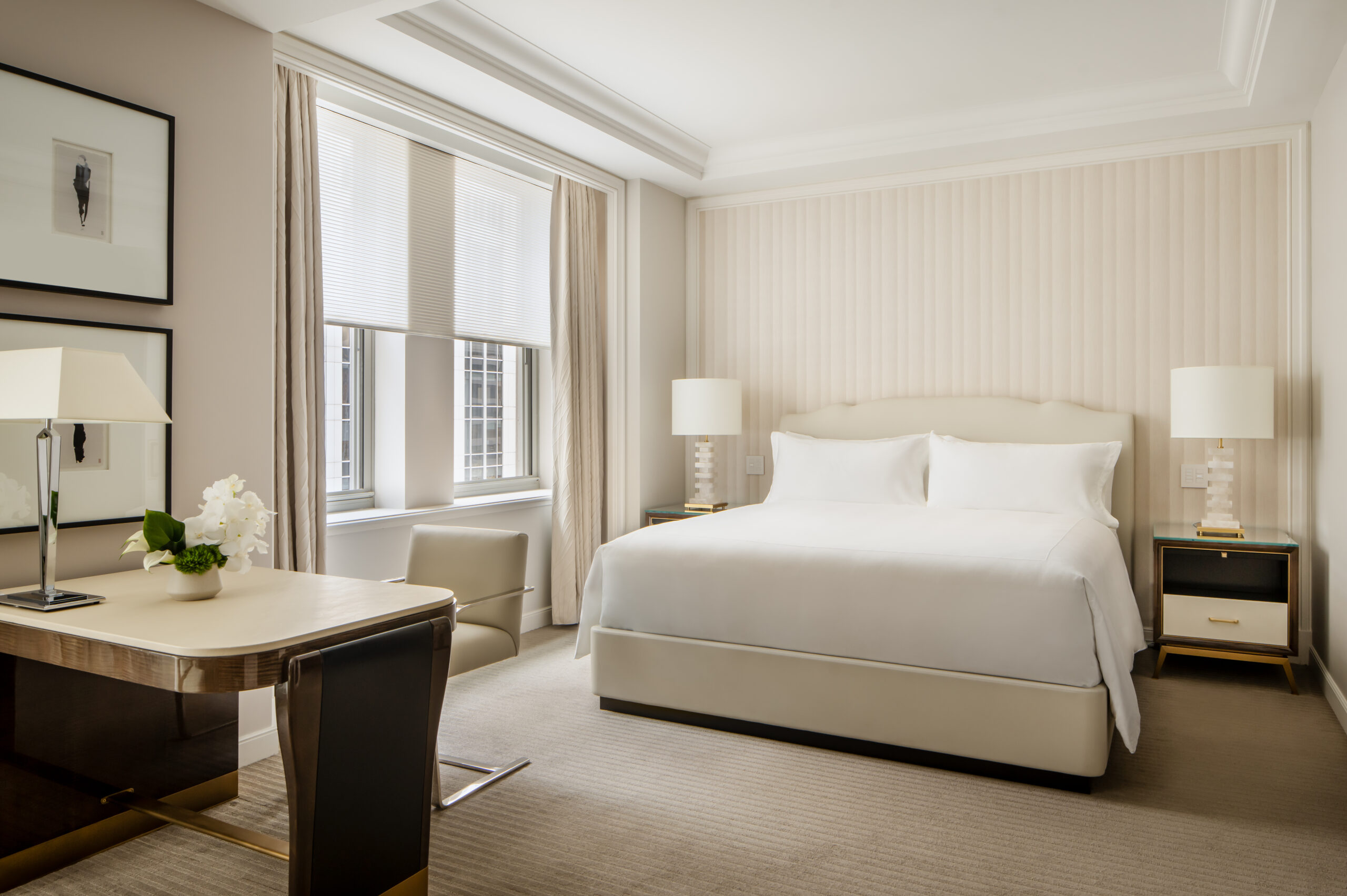 a junior suite room at the Waldorf Astoria with off-white furnishings, a queen-sized bed, and a desk. 