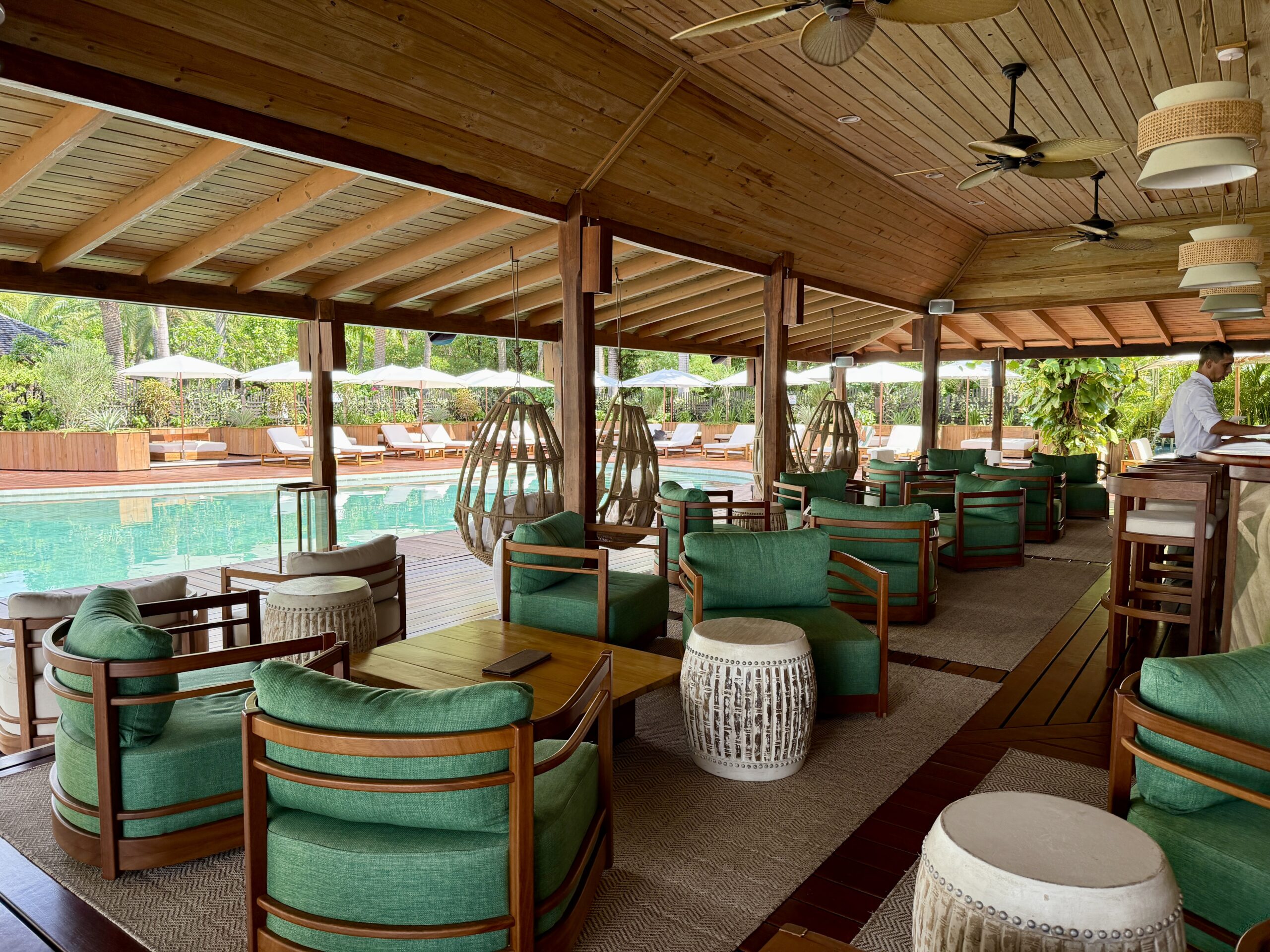 a dozen green armchairs in a bar area with a pool in the background