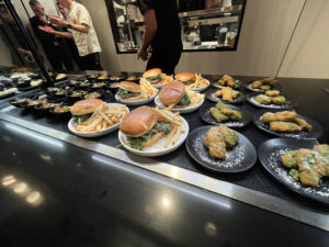 plates and platters with burgers and other food on a warm black surface