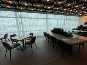 tables with chairs and decorative lighting overhead inside an airport lounge