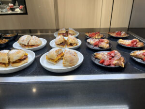 several platters of sandwiches and french toast on a warm black surface